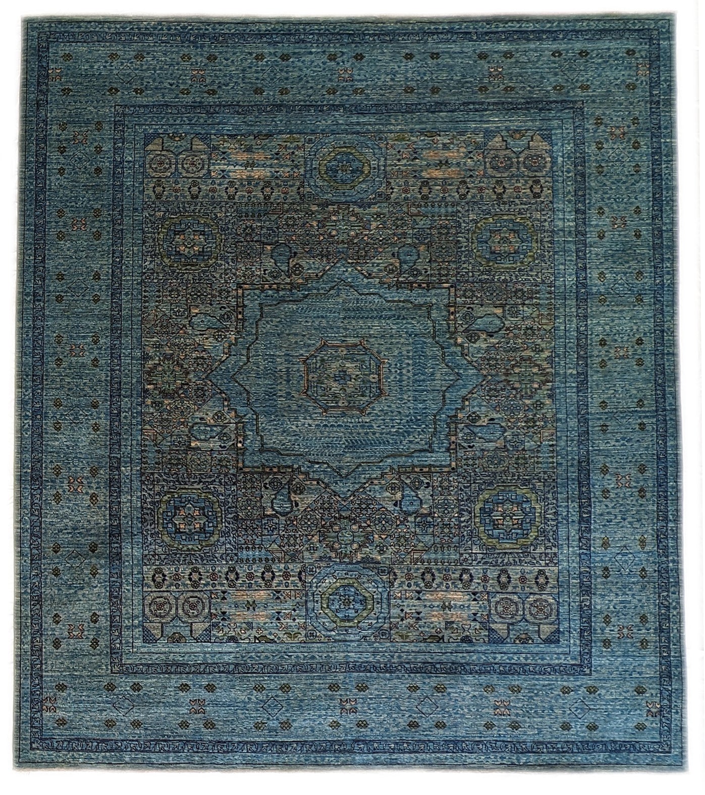 A hand-knotted wool rug with a vivid palette of colors including turquoise, orange, green, eggplant, grey, and navy, featuring intricate tribal patterns.