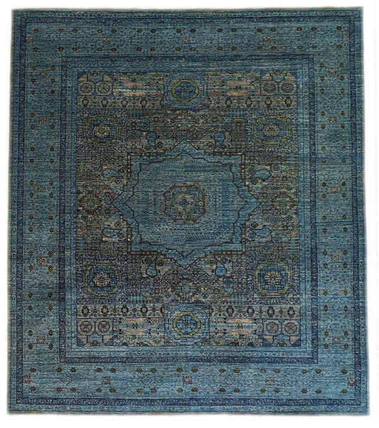 A hand-knotted wool rug with a vivid palette of colors including turquoise, orange, green, eggplant, grey, and navy, featuring intricate tribal patterns.