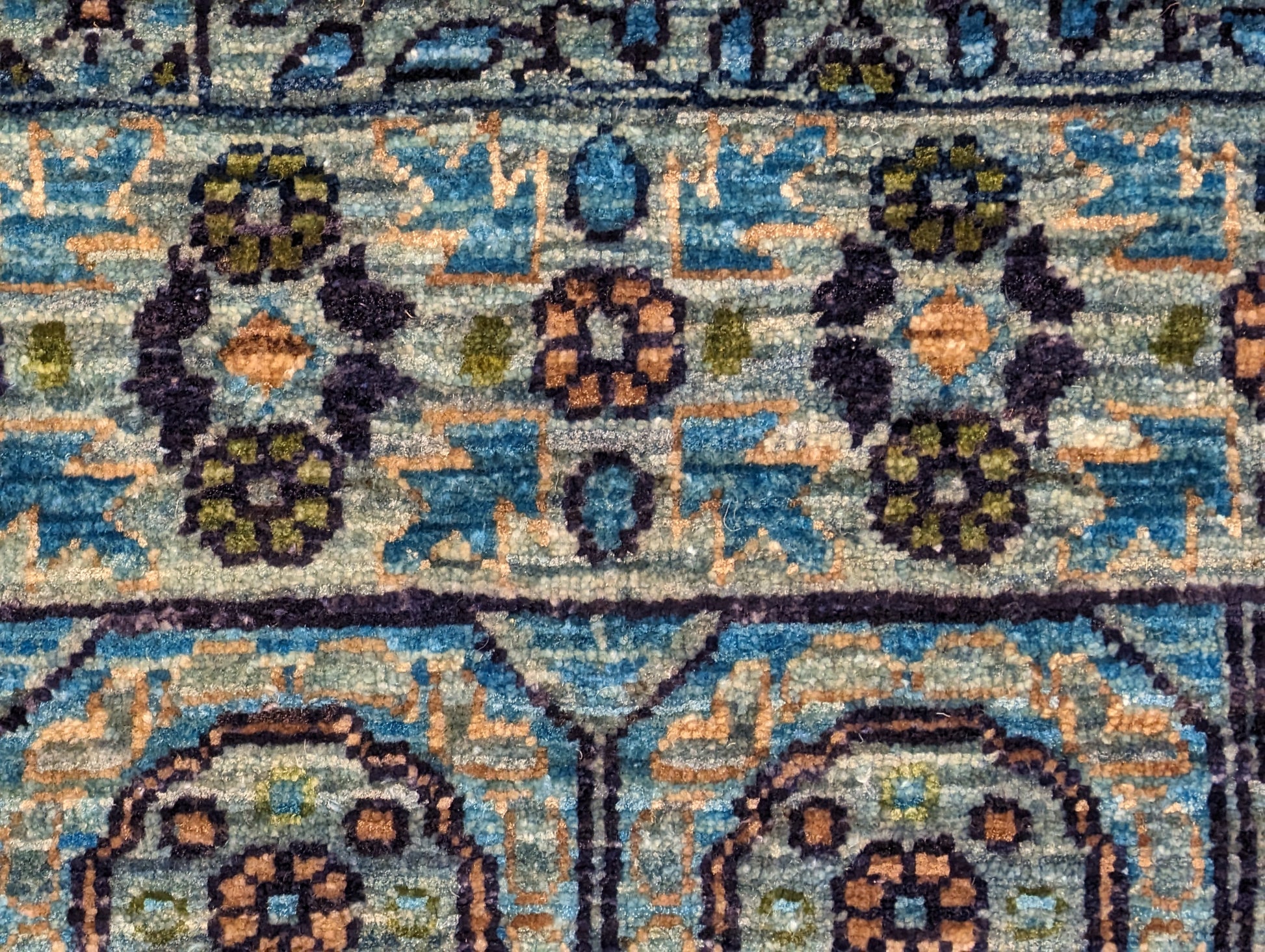 A hand-knotted wool rug with a vivid palette of colors including turquoise, orange, green, eggplant, grey, and navy, featuring intricate tribal patterns.
