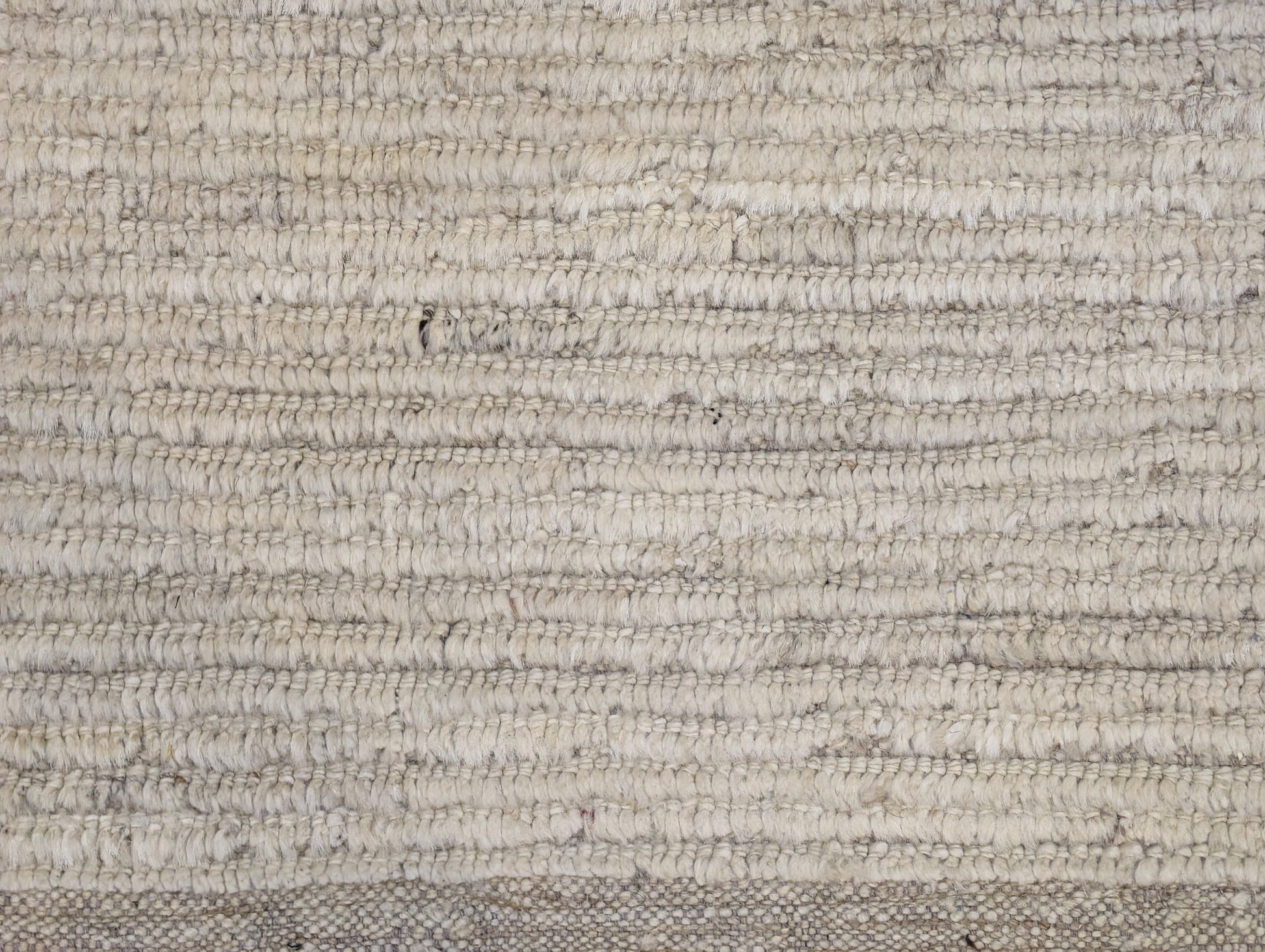 A hand-knotted wool rug in beige, ivory, and cream colors with a coastal aesthetic and a plush appearance.
