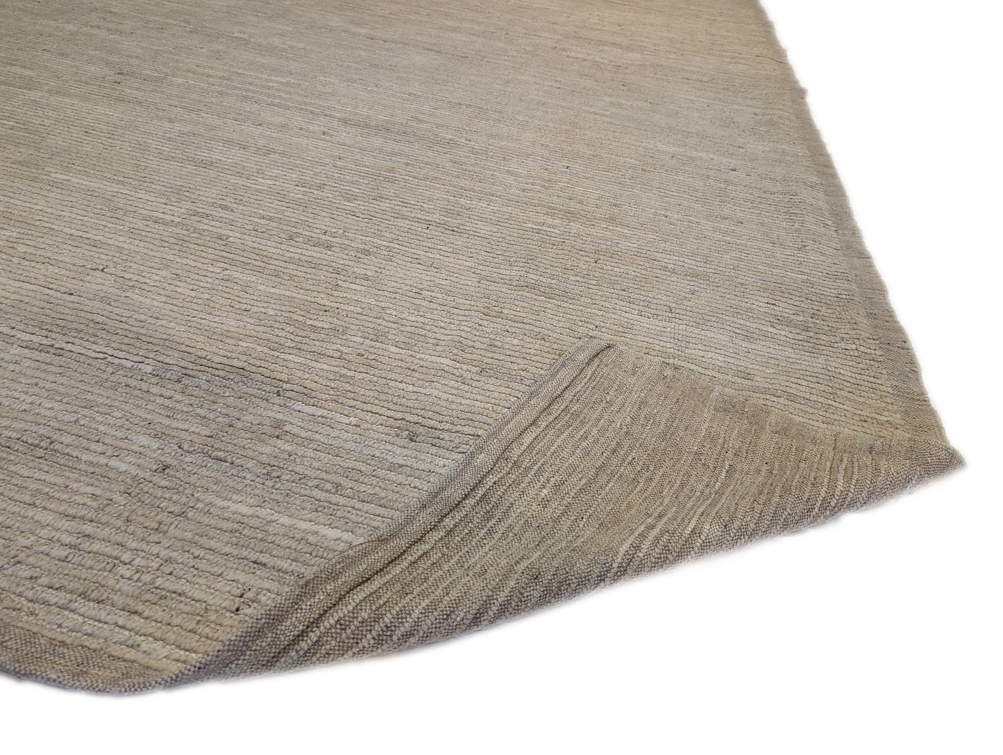 A hand-knotted wool rug in beige, ivory, and cream colors with a coastal aesthetic and a plush appearance.