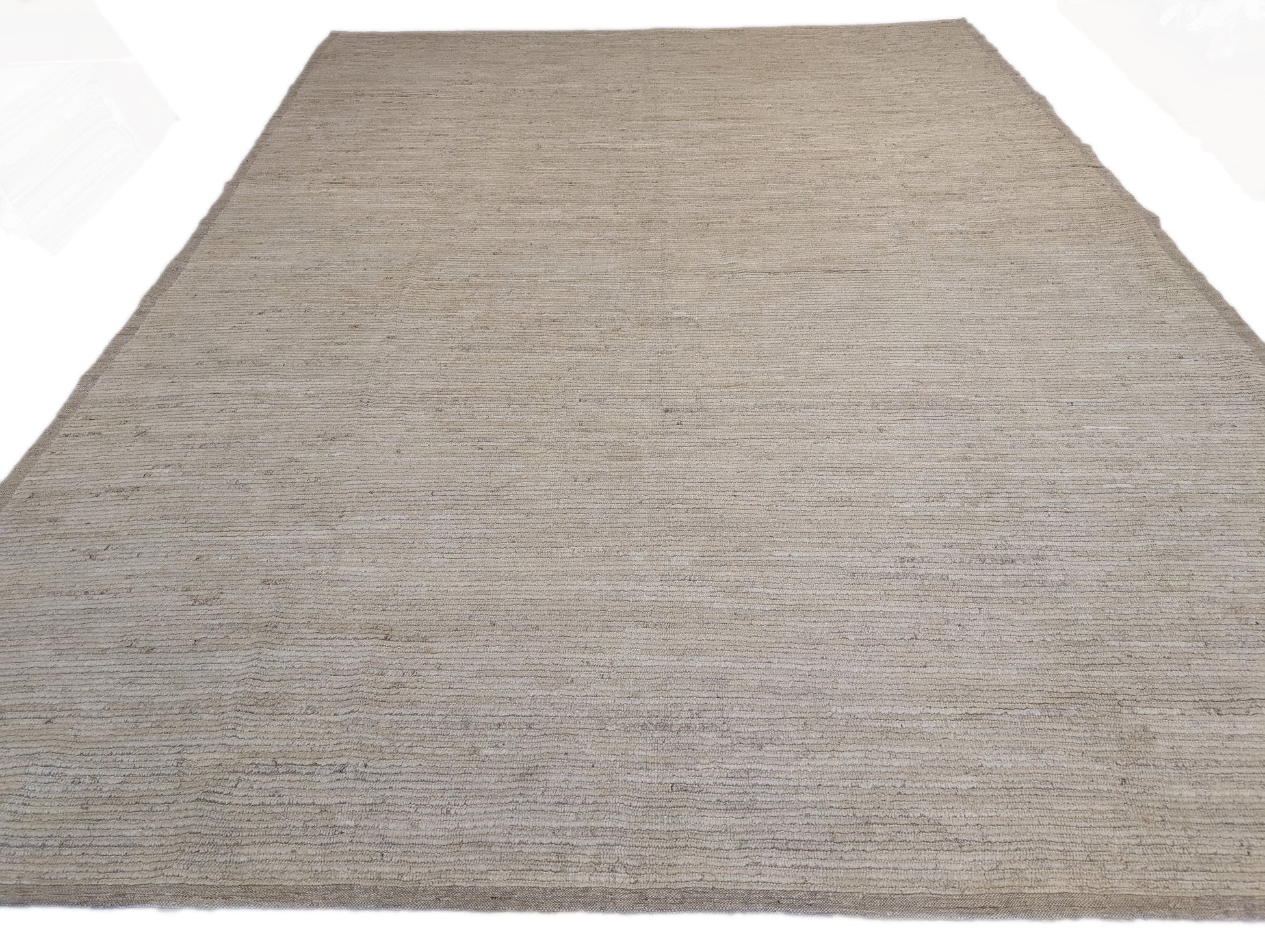 A hand-knotted wool rug in beige, ivory, and cream colors with a coastal aesthetic and a plush appearance.