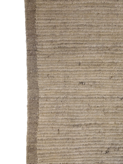 A hand-knotted wool rug in beige, ivory, and cream colors with a coastal aesthetic and a plush appearance.