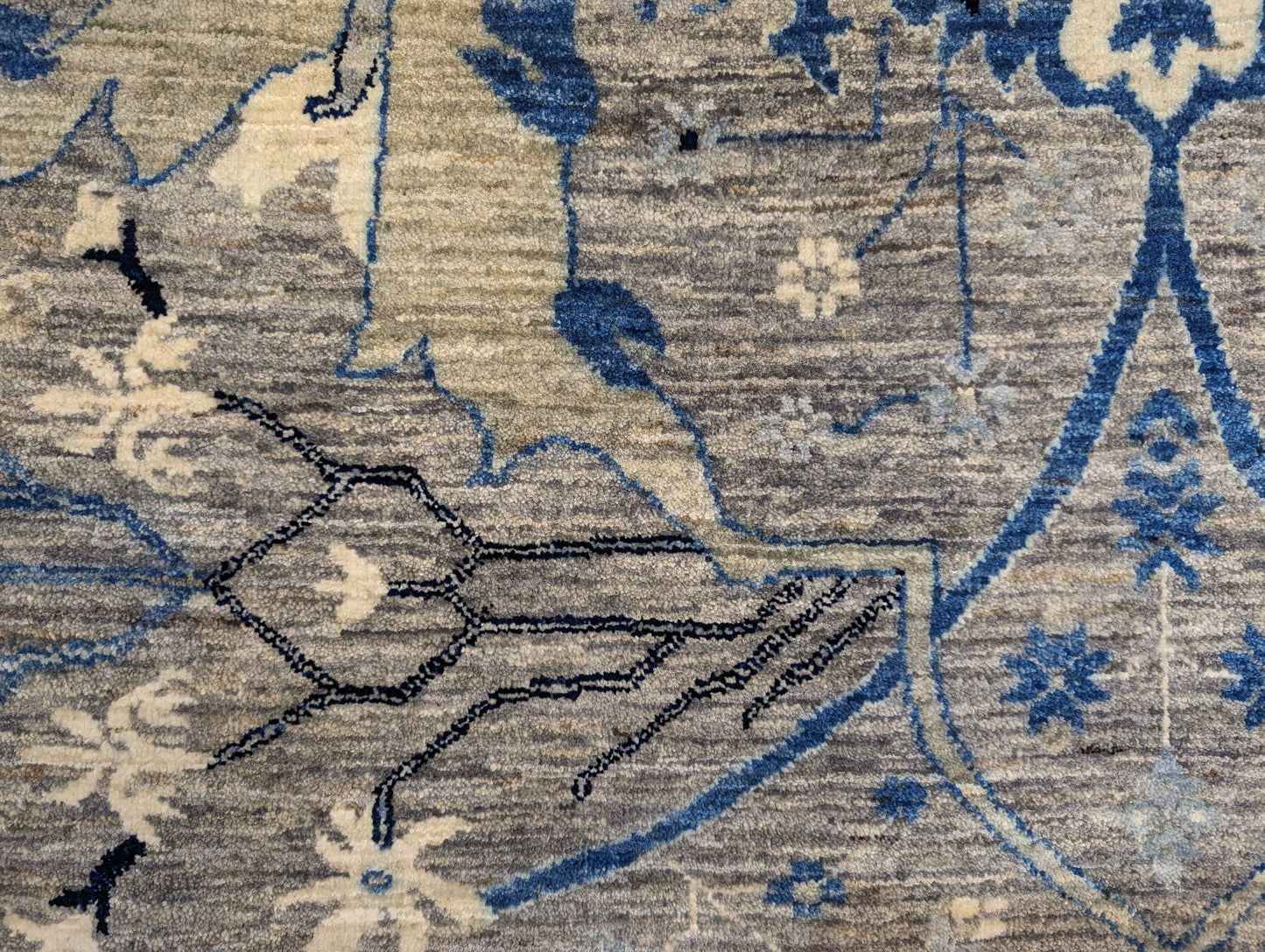 A hand-knotted wool rug with a coastal color palette, featuring traditional and contemporary geometric patterns.