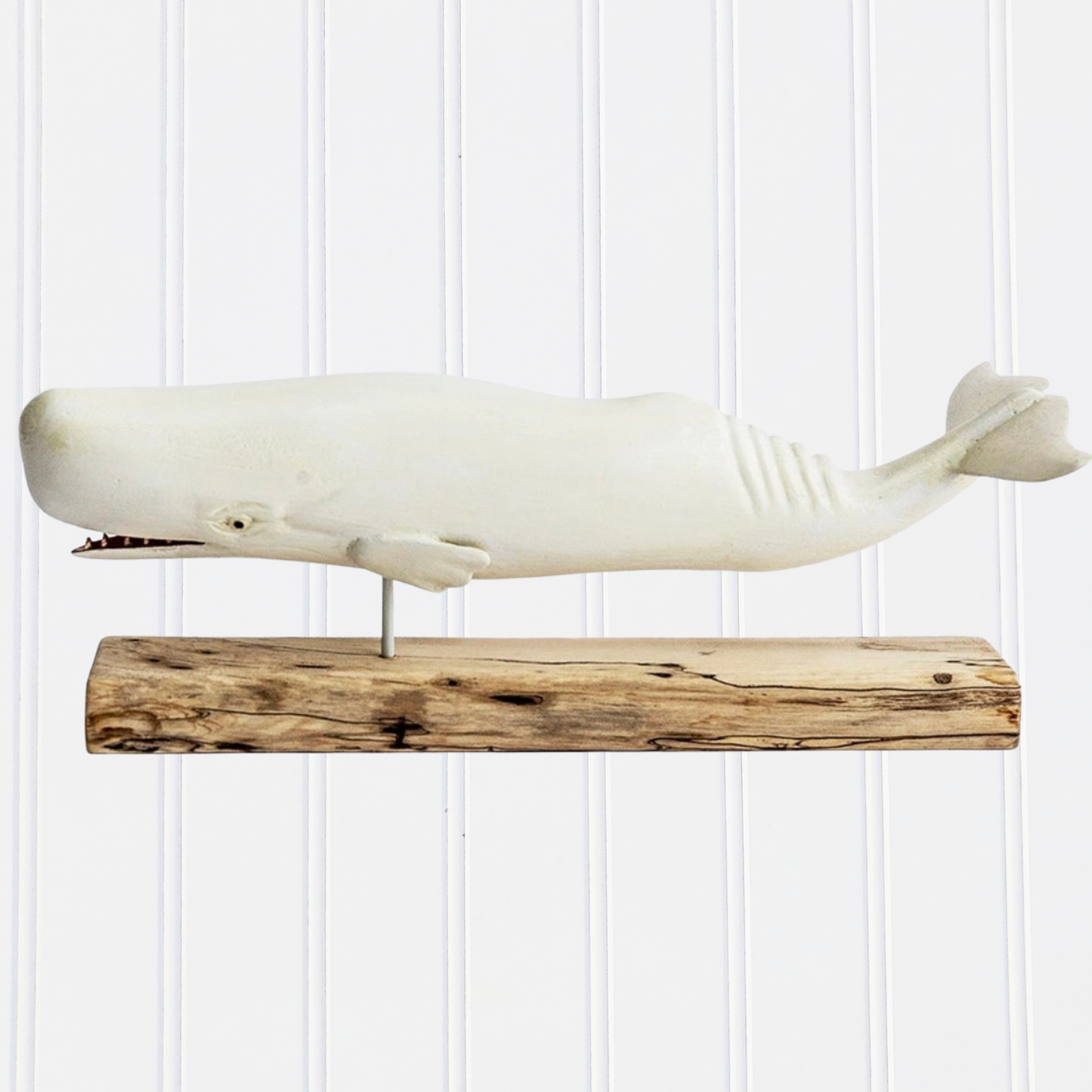 Decorative whale sculpture on a wooden base against a white paneled wall
