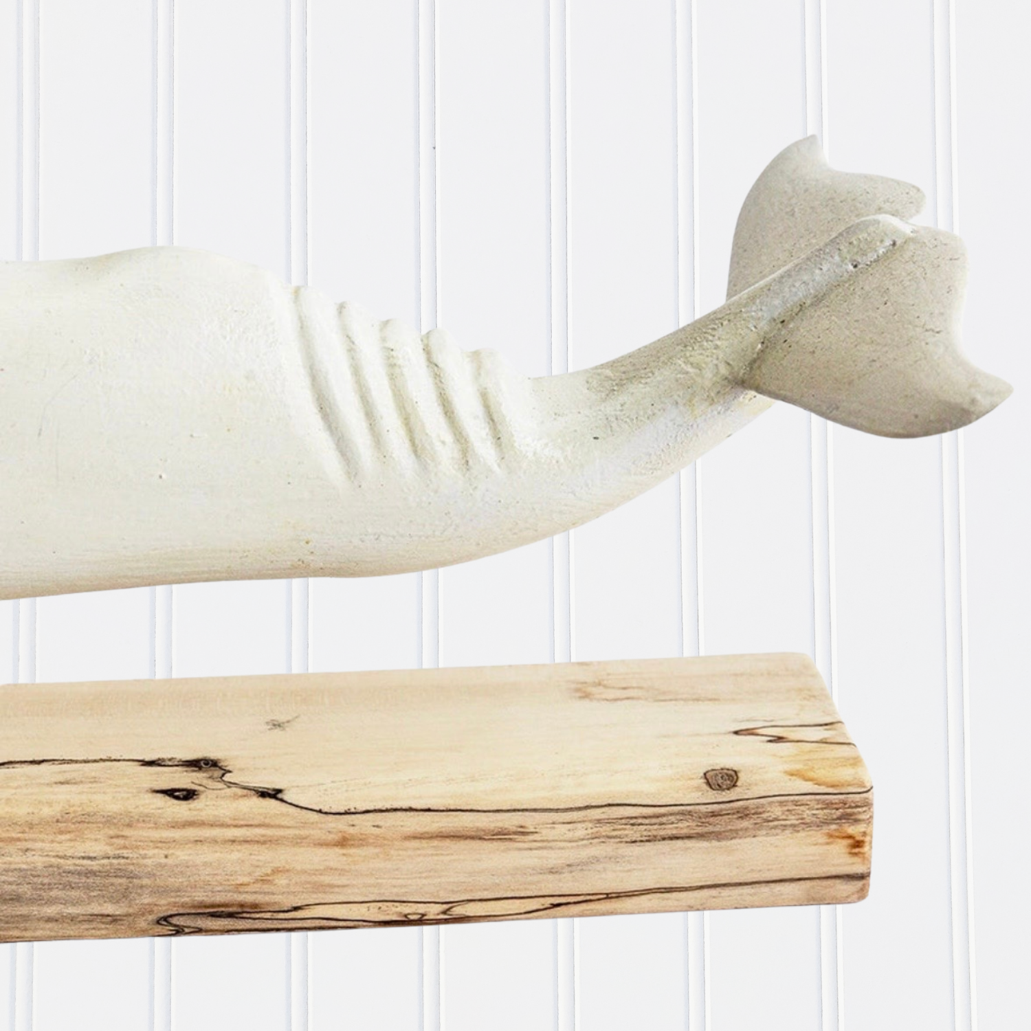 Decorative whale sculpture on a wooden shelf against a white paneled wall