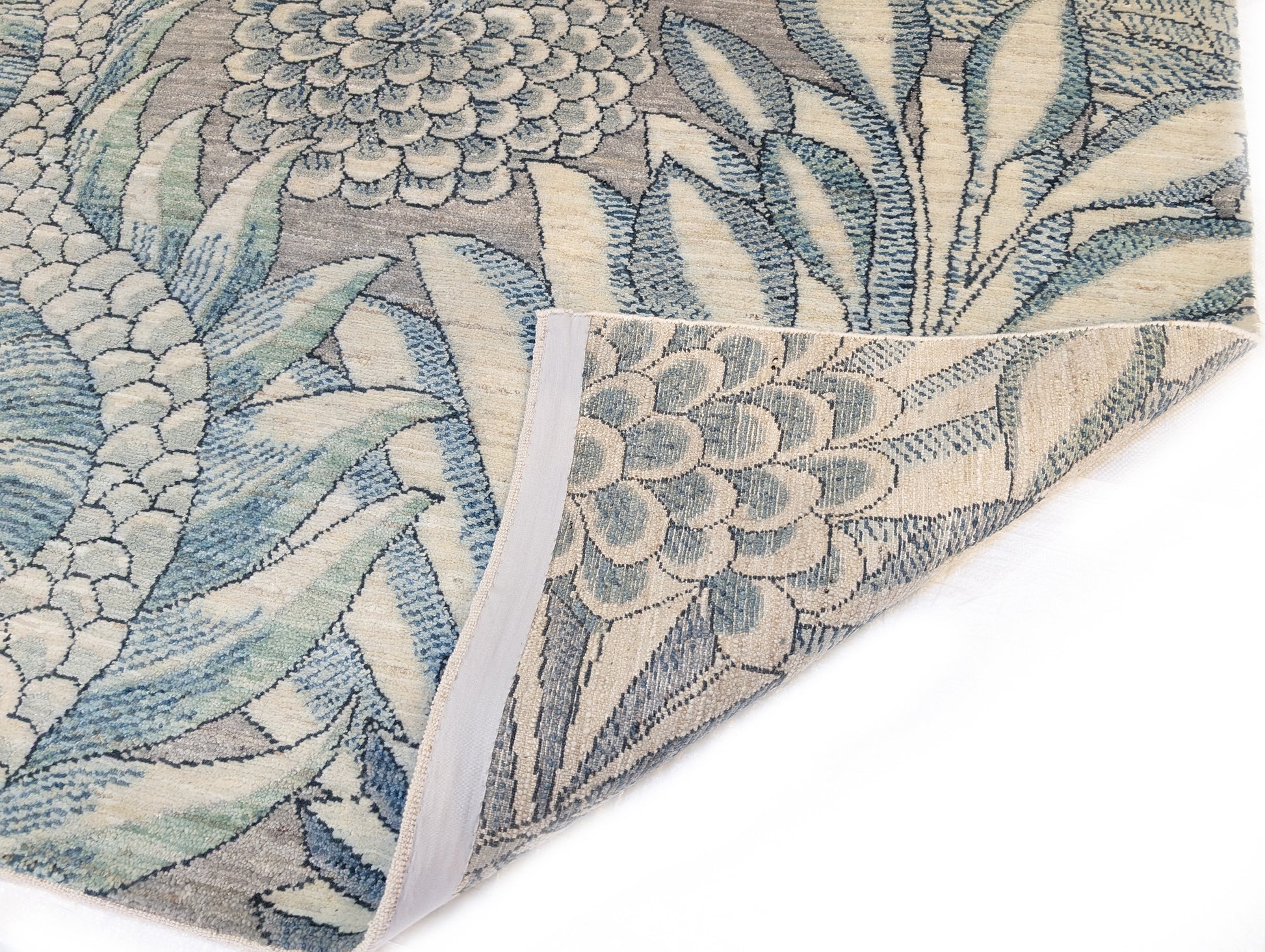 A hand-knotted wool rug with a coastal-inspired floral and plant design in shades of beige, gray, blue, green, and black.