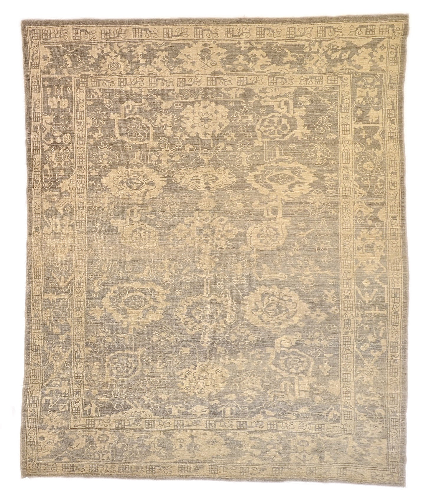 An antique-style beige and neutral-colored rug with a floral and geometric pattern, hand-knotted with low pile.