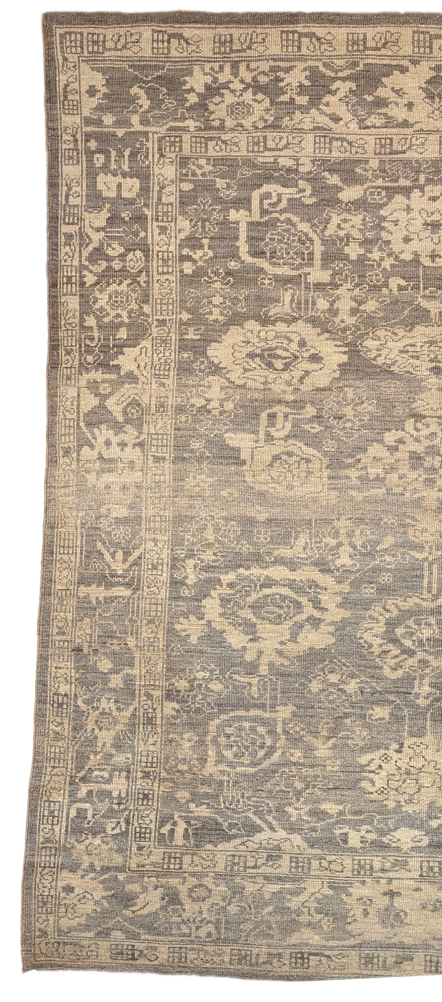 An antique-style beige and neutral-colored rug with a floral and geometric pattern, hand-knotted with low pile.
