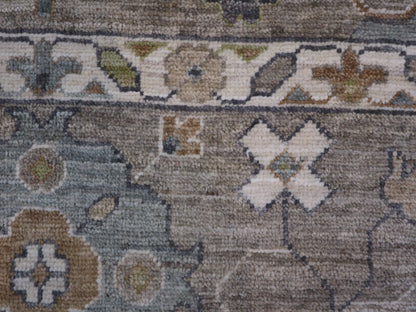 A hand-knotted wool rug with a coastal design in shades of grey, blue, ivory, brown, orange, green, and taupe.