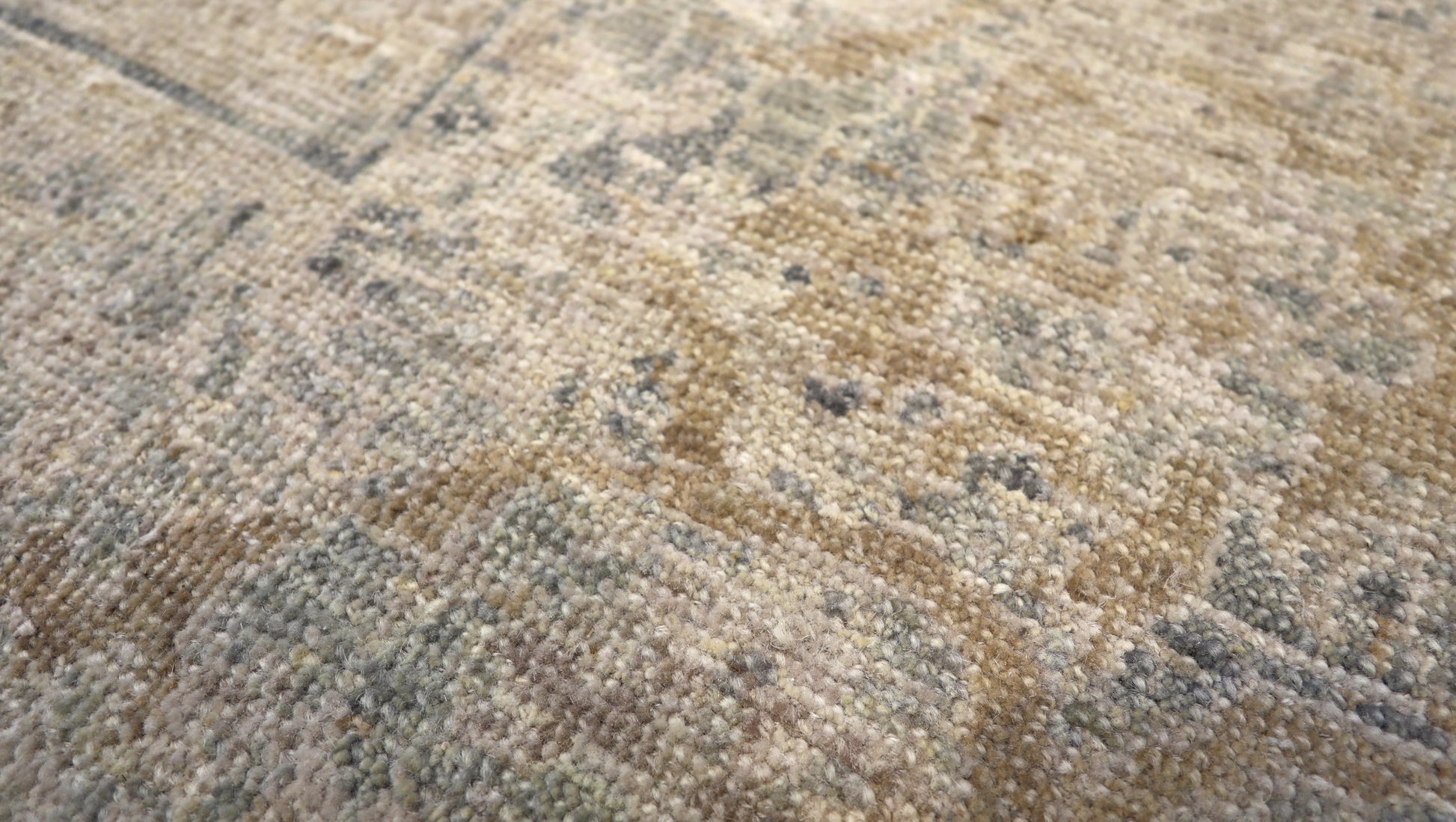 Hand-knotted wool rug with an antique finish in sun-bleached sand, seashell ivory, ocean blue, and driftwood gray.