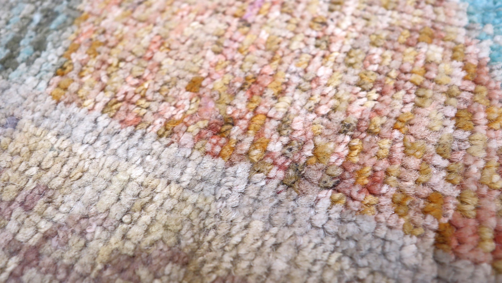 Hand- Knotted multicolored geometric patterned rug with shades of beige, blue, orange, and red.