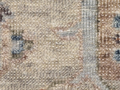 A hand-knotted wool rug with a traditional and coastal design in beige, blue, brown, and gold colors.
