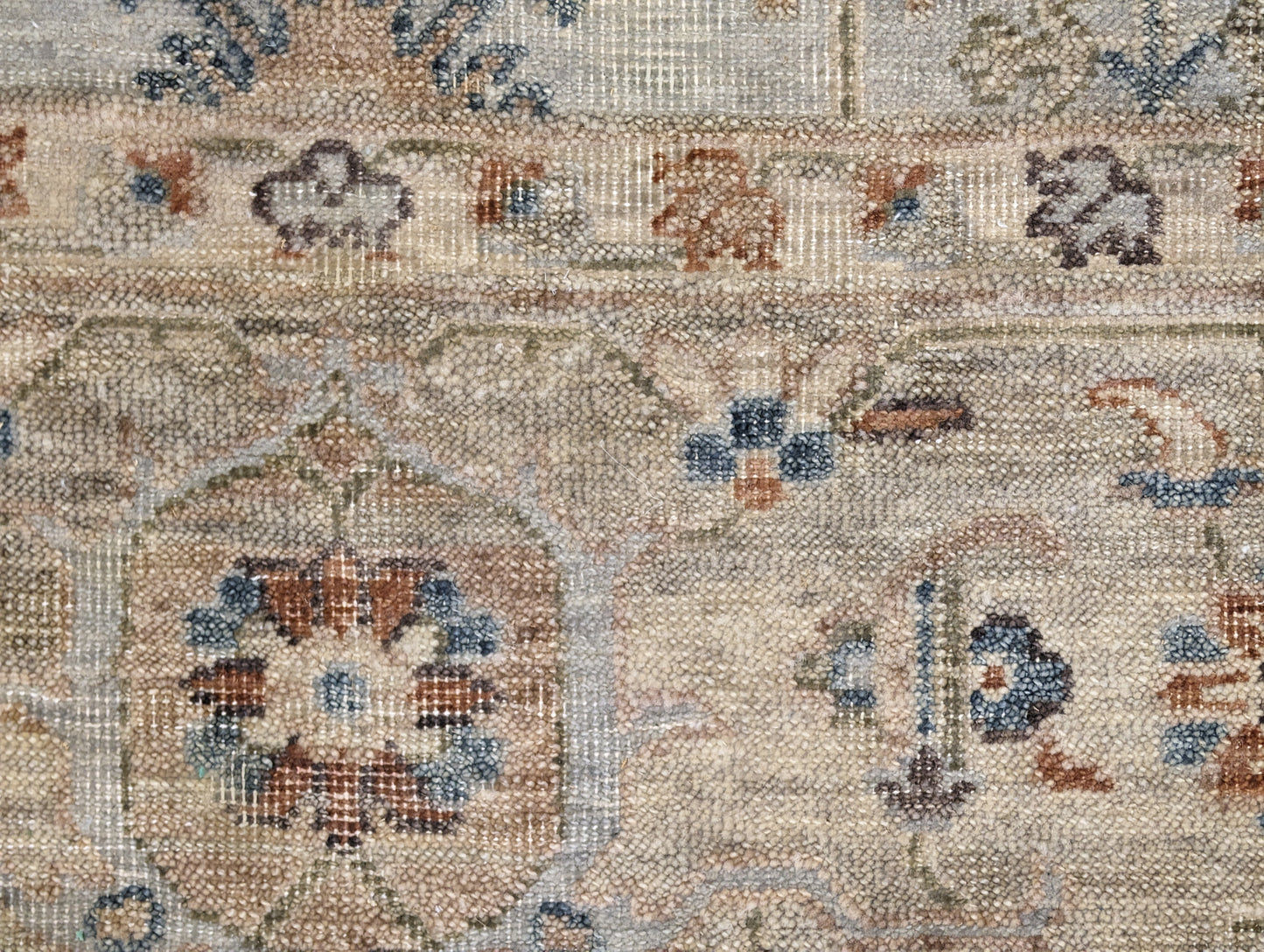 A hand-knotted wool rug with a traditional and coastal design in beige, blue, brown, and gold colors.