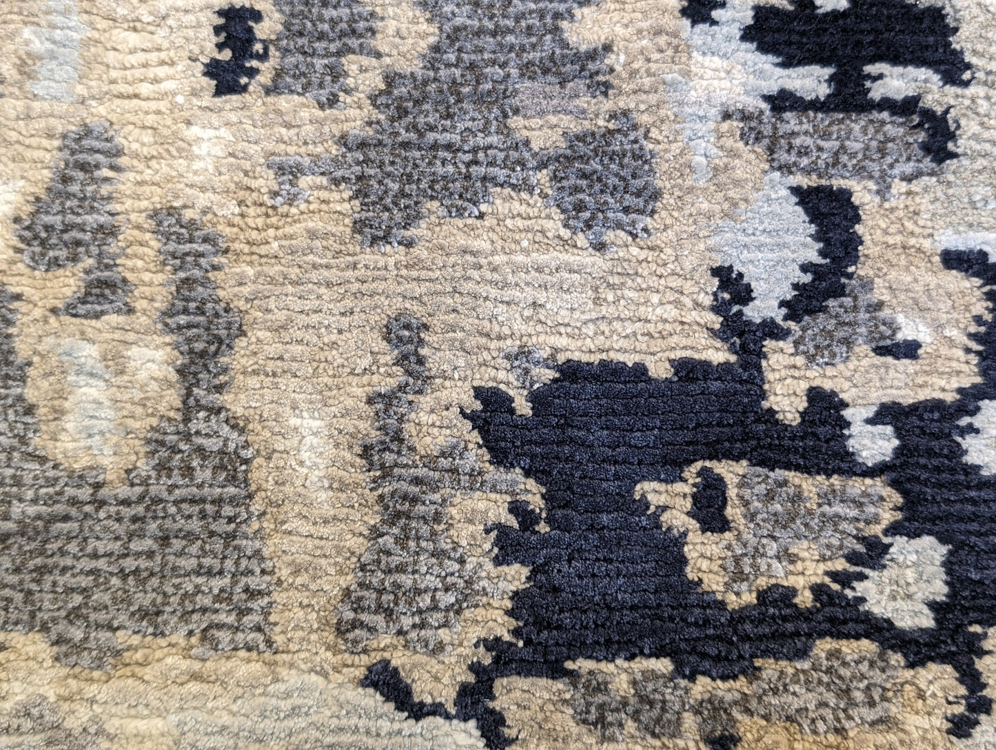 A luxurious coastal-themed rug featuring a blend of beige, gray, blue, and green colors with a textured and rugged texture. Wool and silk. 