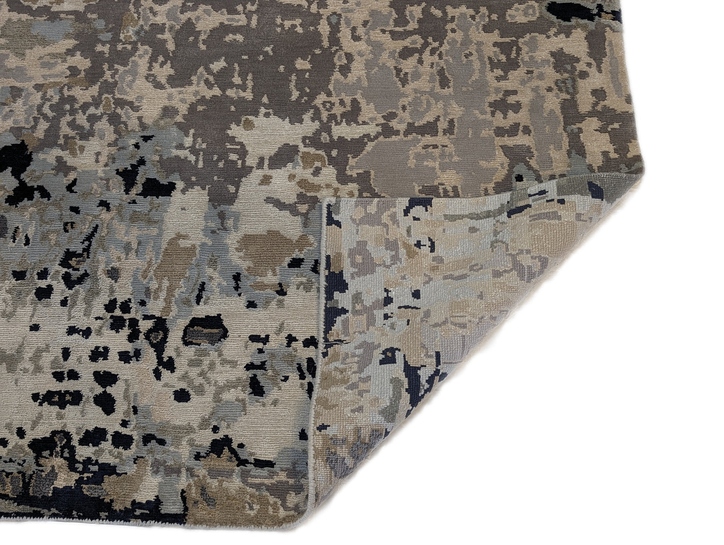 A luxurious coastal-themed rug featuring a blend of beige, gray, blue, and green colors with a textured and rugged texture. Wool and silk. 