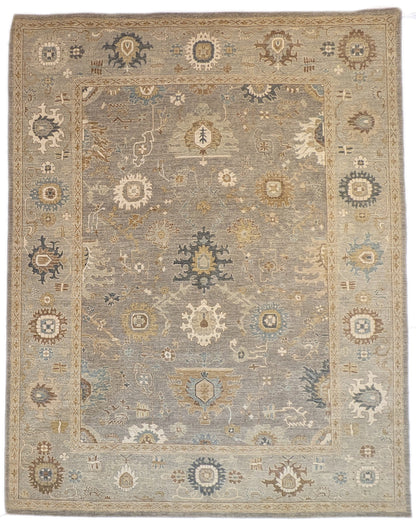 A hand-knotted wool rug featuring a coastal pattern with shades of beige, blue, brown, bronze, gold, ivory, and grey.
