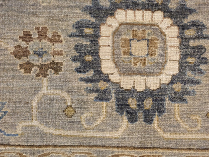 A hand-knotted wool rug featuring a coastal pattern with shades of beige, blue, brown, bronze, gold, ivory, and grey.