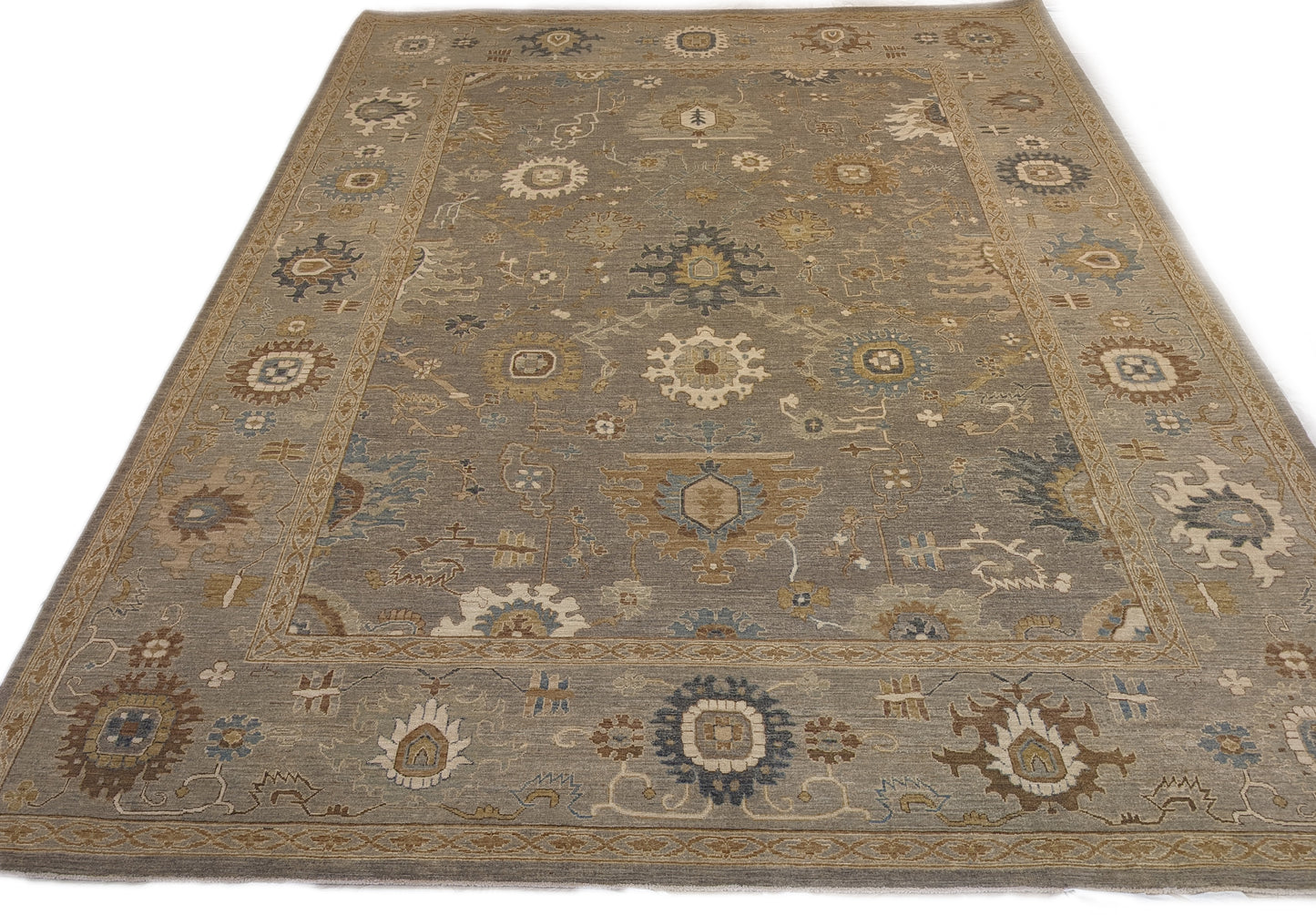 A hand-knotted wool rug featuring a coastal pattern with shades of beige, blue, brown, bronze, gold, ivory, and grey.