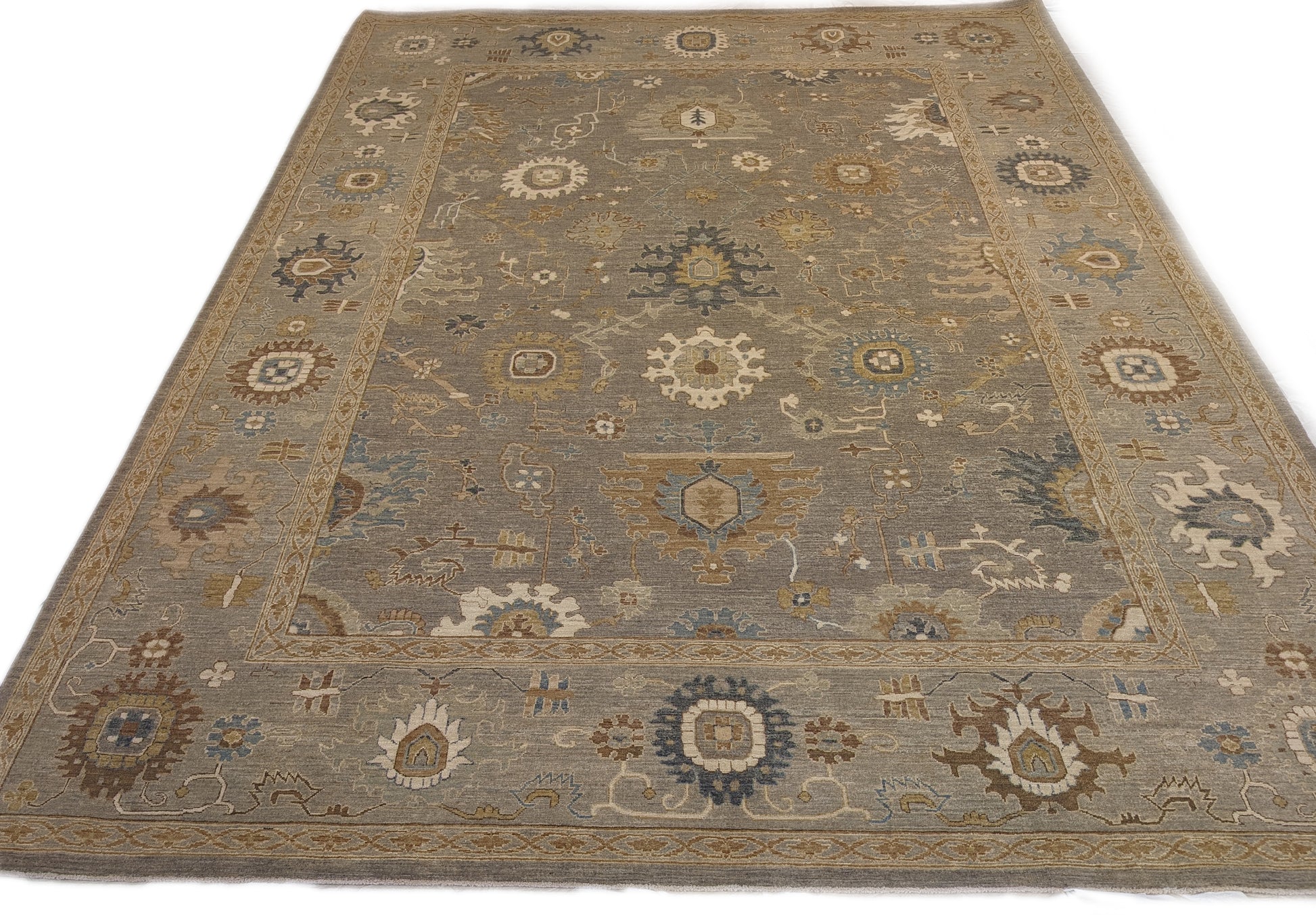 A hand-knotted wool rug featuring a coastal pattern with shades of beige, blue, brown, bronze, gold, ivory, and grey.