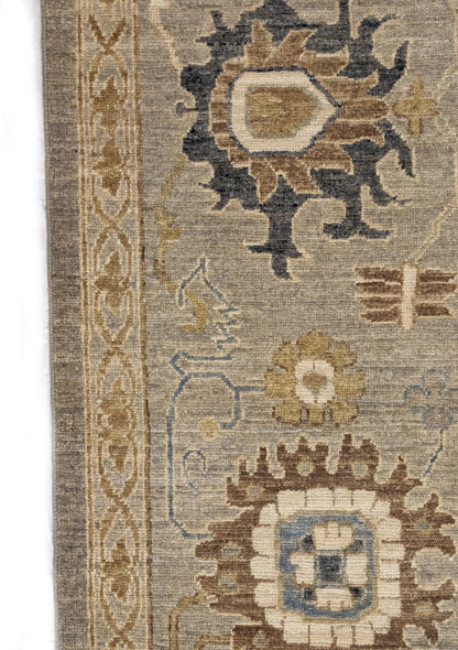 A hand-knotted wool rug featuring a coastal pattern with shades of beige, blue, brown, bronze, gold, ivory, and grey.
