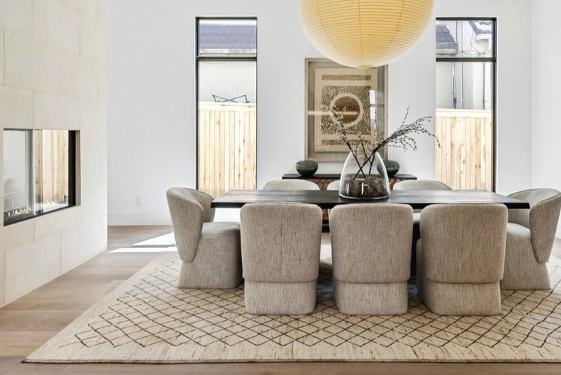 Modern dining room with a long table and chairs, featuring a large round pendant light.