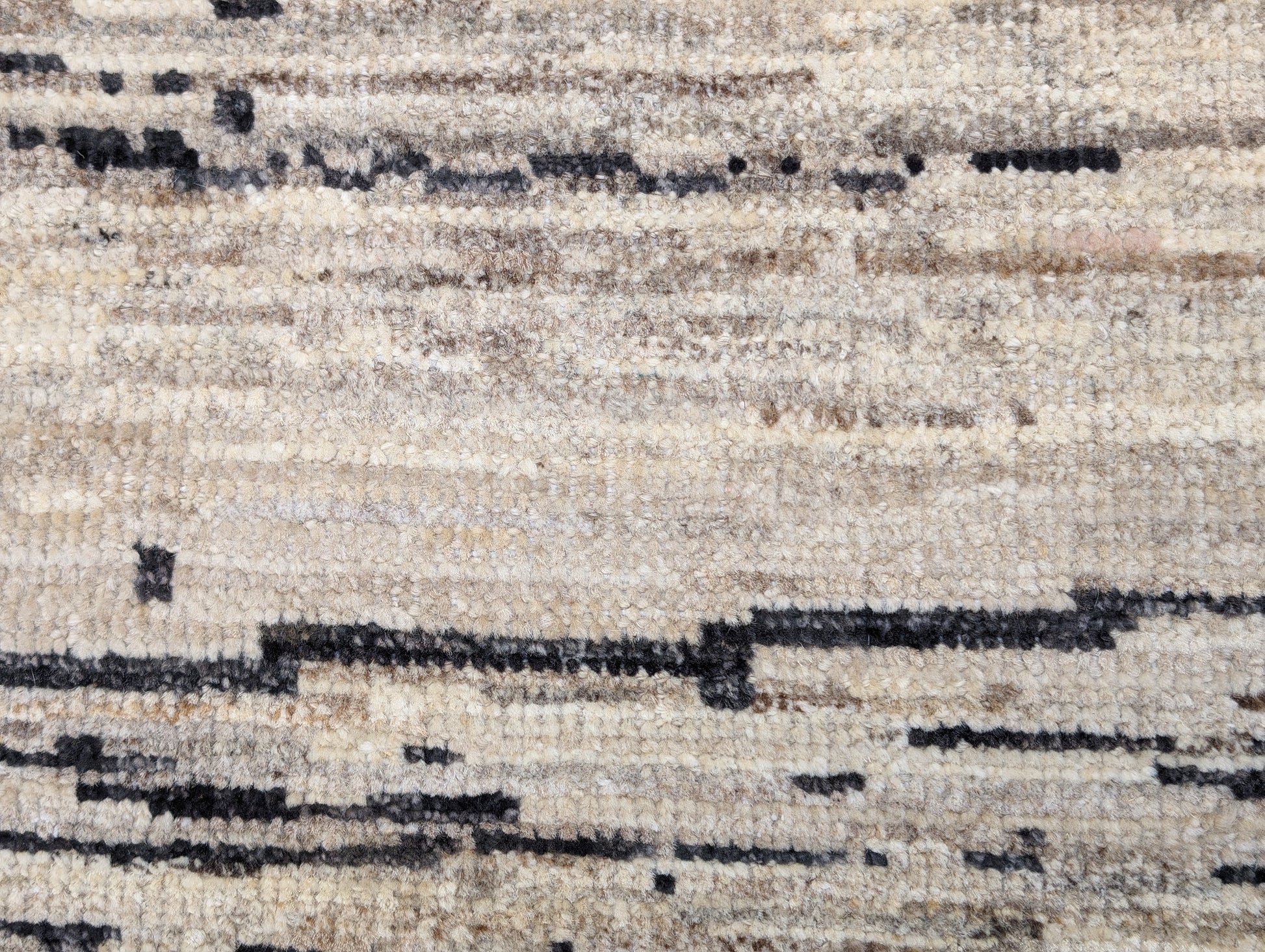 A hand-knotted wool rug with a cozy pile, featuring natural tones of ivory, beige, gray, and brown.