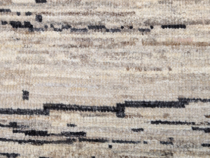 A hand-knotted wool rug with a cozy pile, featuring natural tones of ivory, beige, gray, and brown.