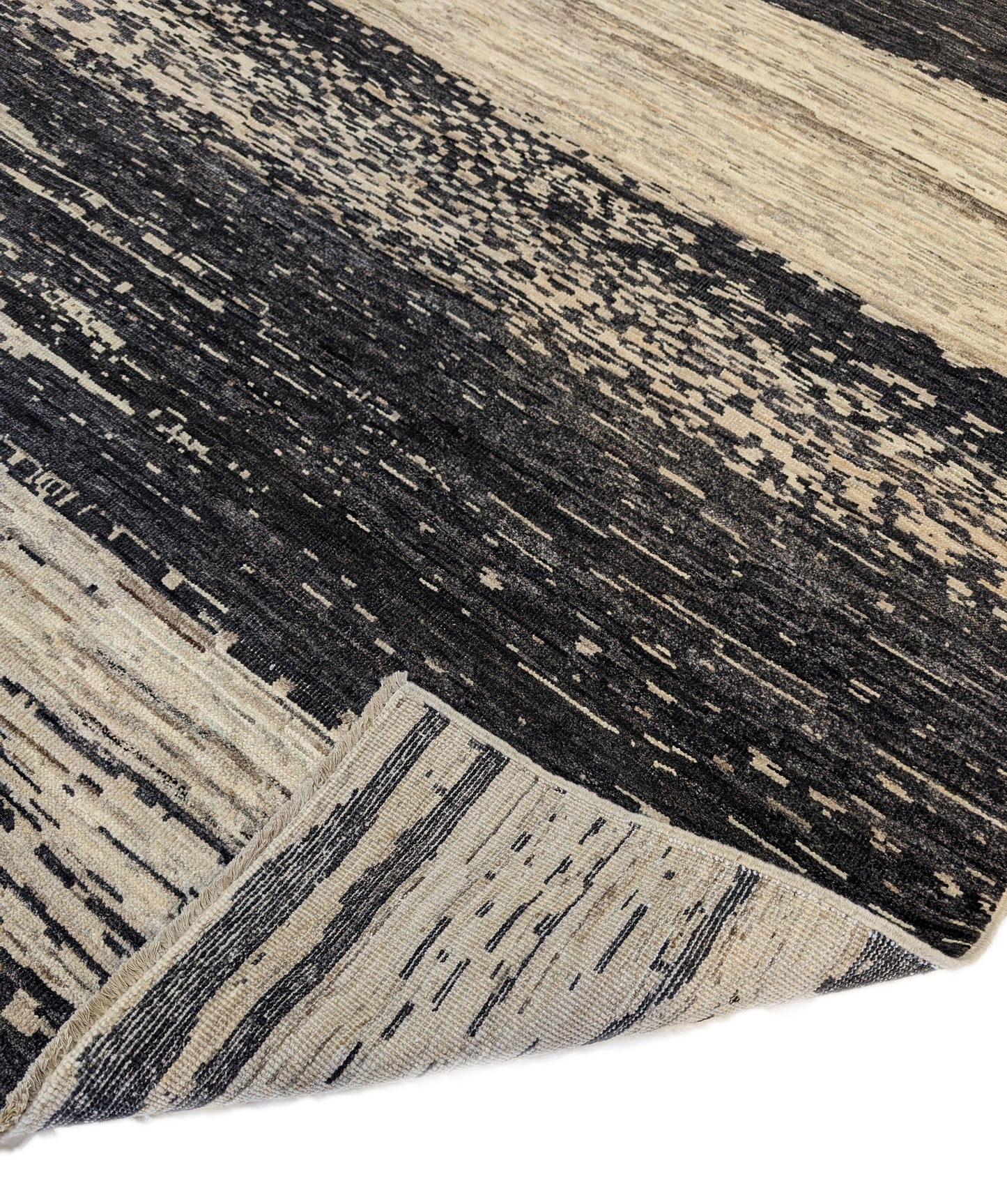A hand-knotted wool rug with a cozy pile, featuring natural tones of ivory, beige, gray, and brown.