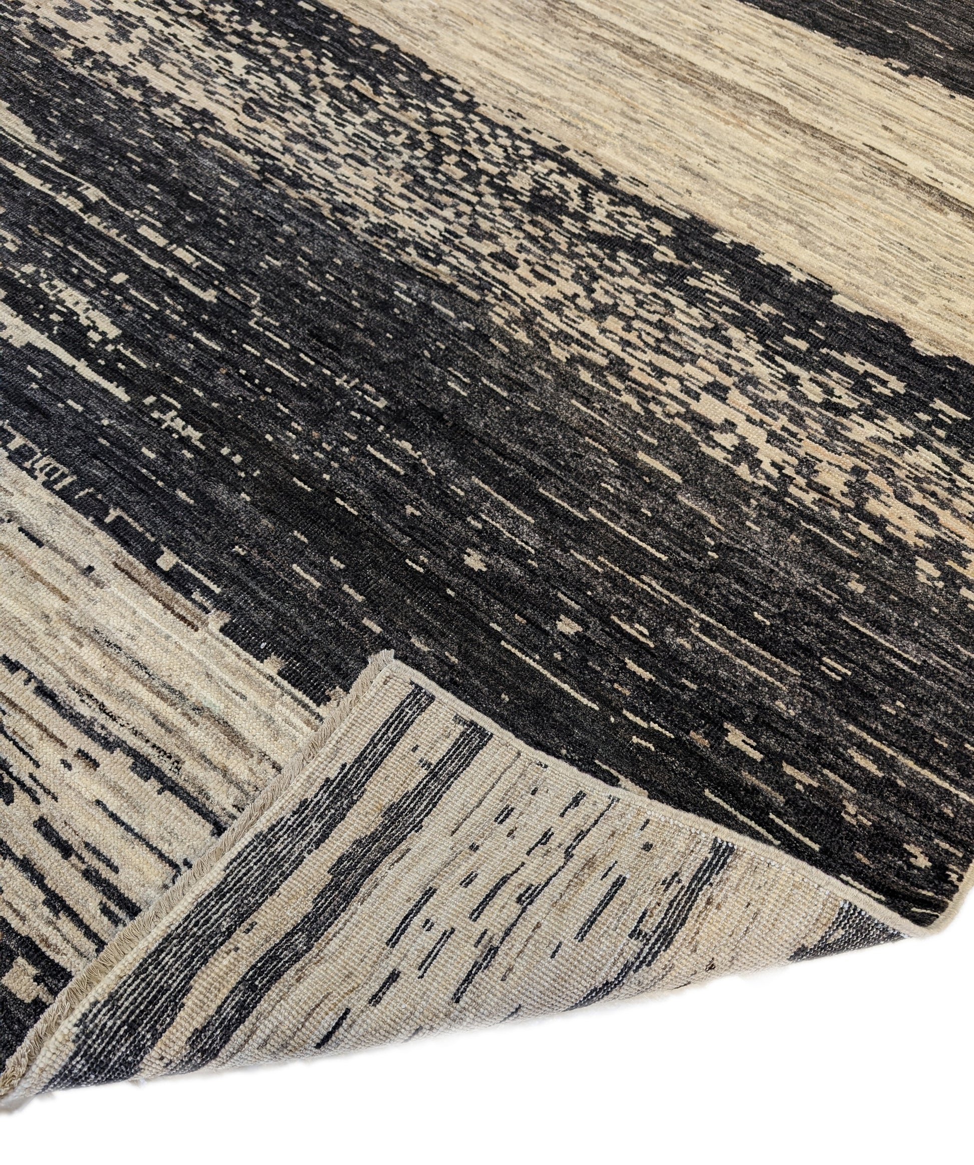 A hand-knotted wool rug with a cozy pile, featuring natural tones of ivory, beige, gray, and brown.