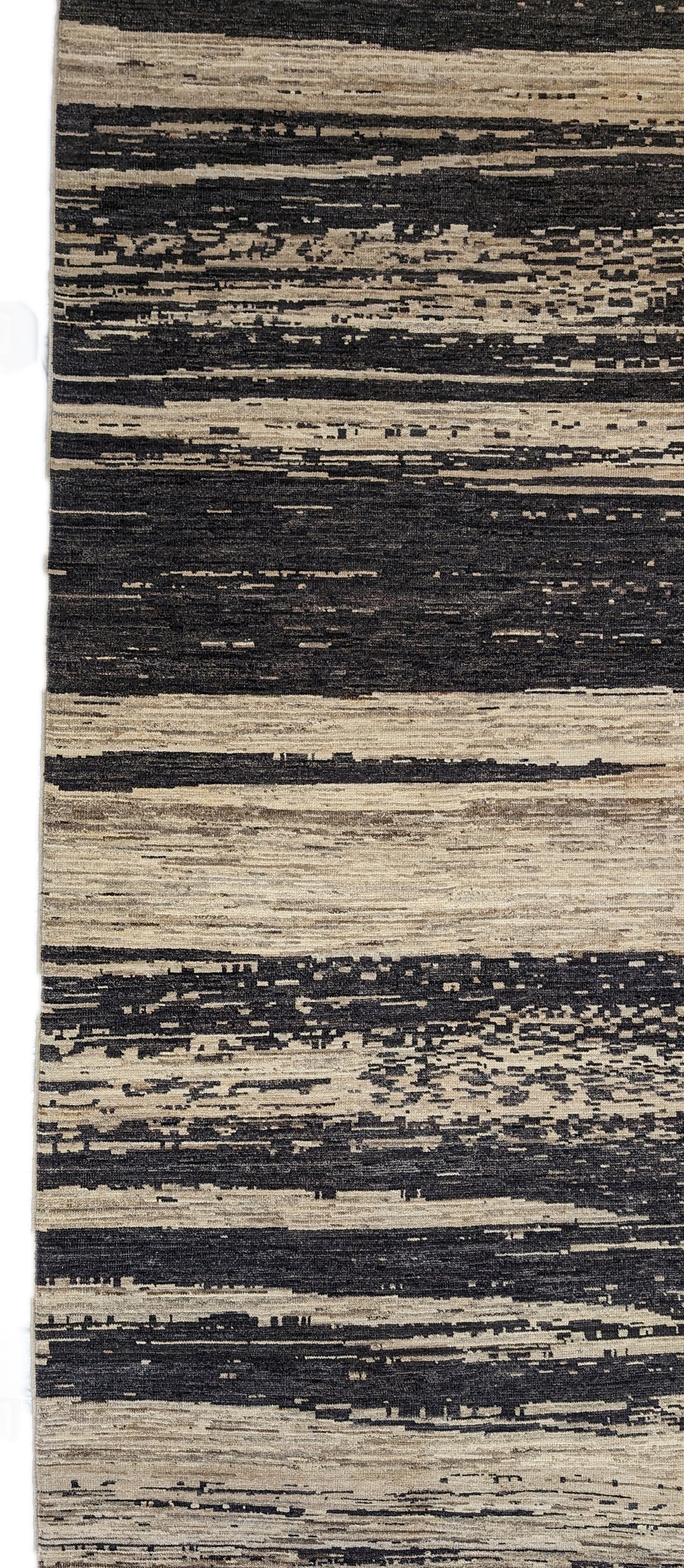 A hand-knotted wool rug with a cozy pile, featuring natural tones of ivory, beige, gray, and brown.