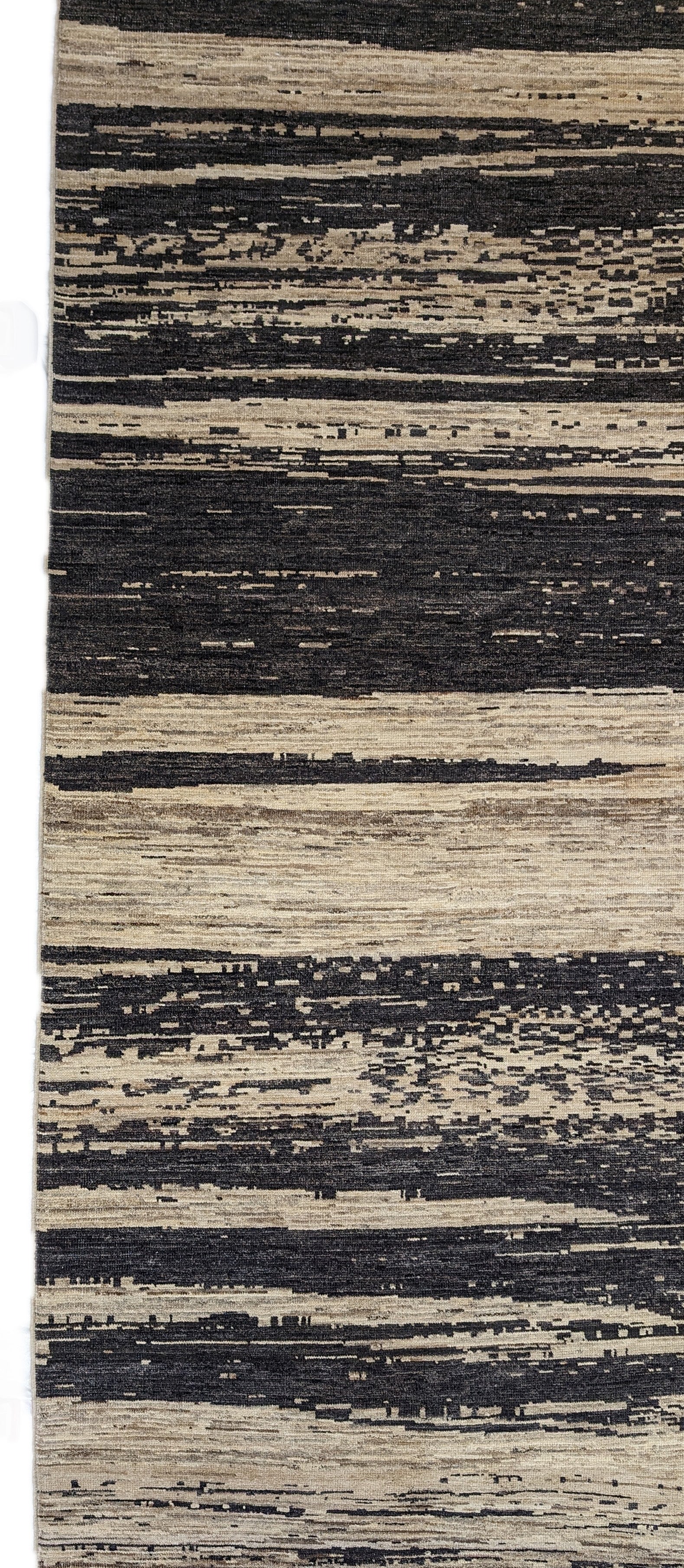 A hand-knotted wool rug with a cozy pile, featuring natural tones of ivory, beige, gray, and brown.