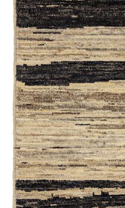 A hand-knotted wool rug with a cozy pile, featuring natural tones of ivory, beige, gray, and brown.