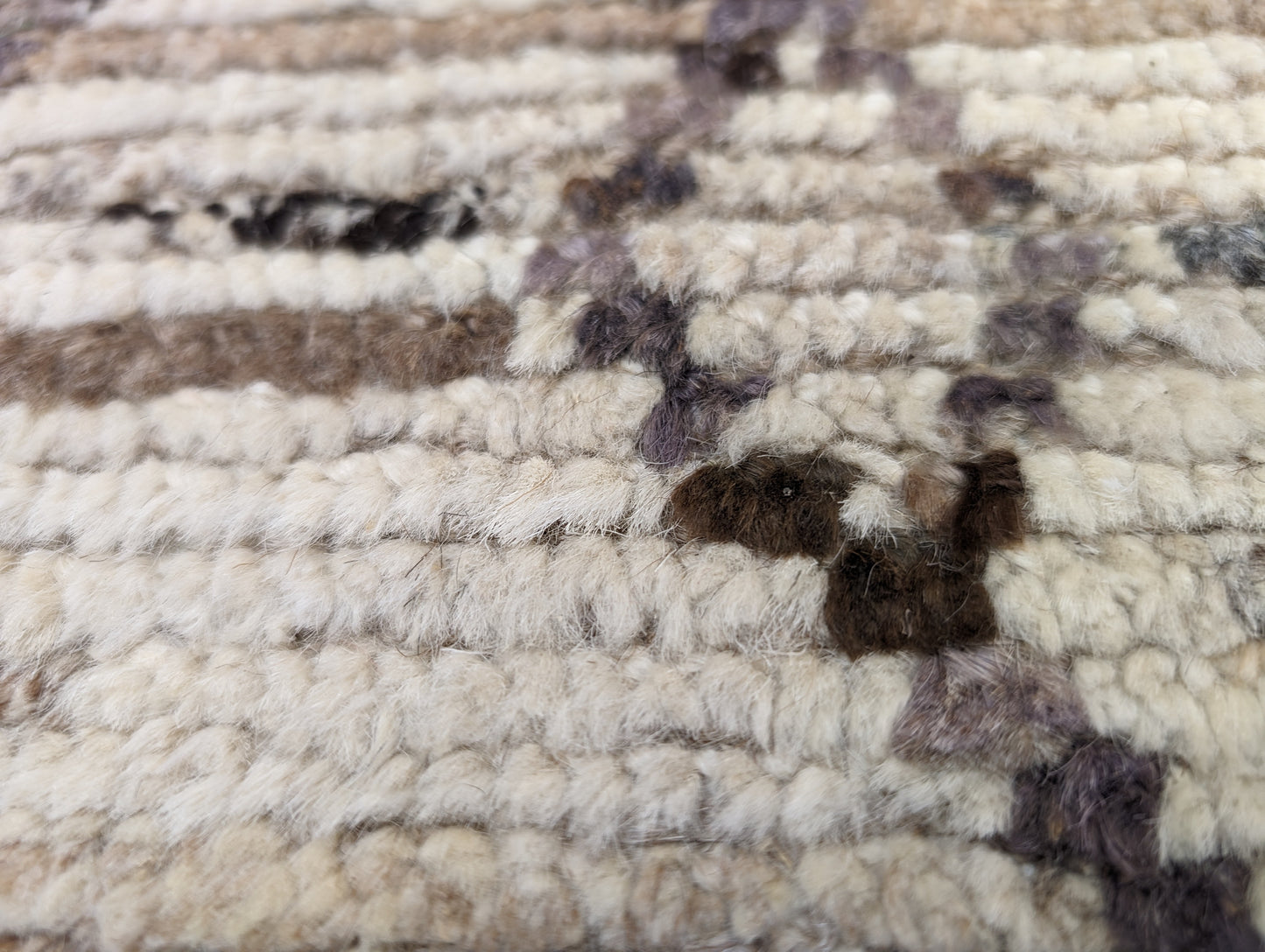 A hand-knotted wool rug with a geometric pattern in natural tones of beige, brown, and gray. Cozy pile.