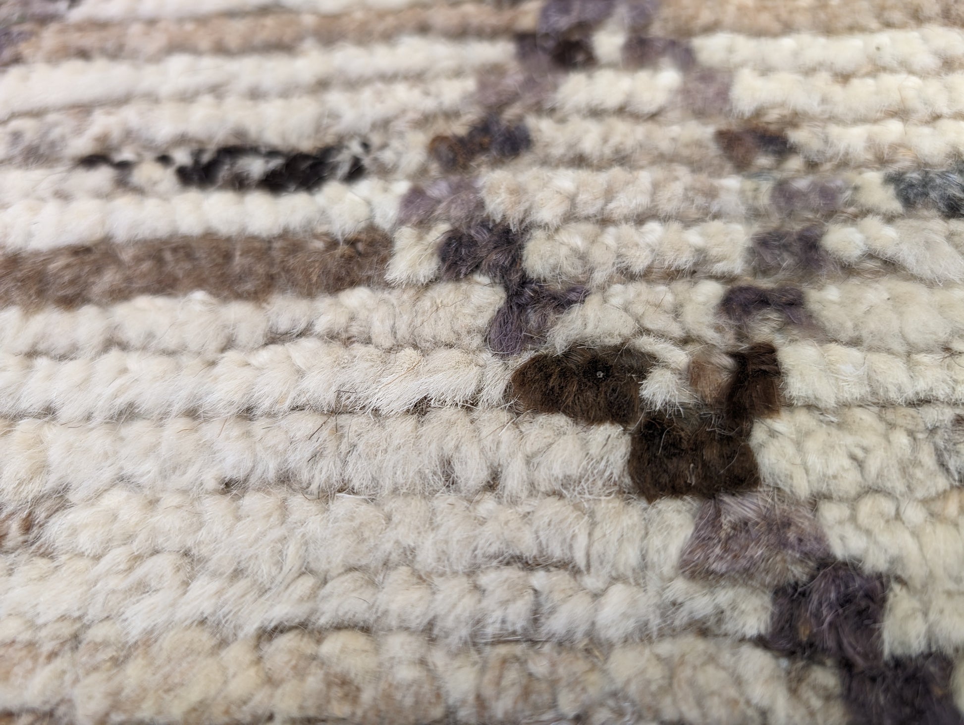 A hand-knotted wool rug with a geometric pattern in natural tones of beige, brown, and gray. Cozy pile.