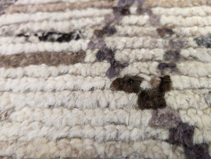 A hand-knotted wool rug with a geometric pattern in natural tones of beige, brown, and gray. Cozy pile.