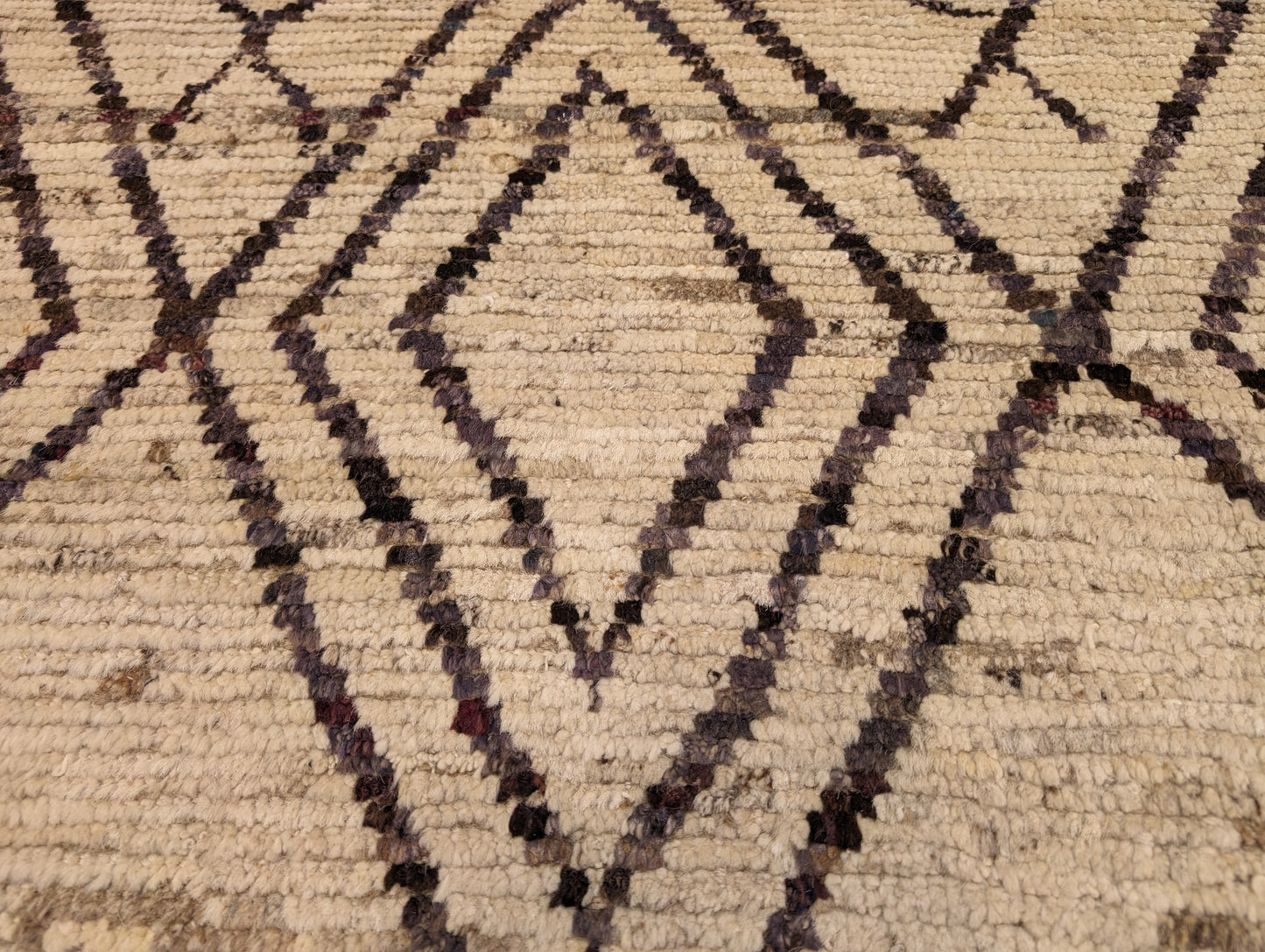 A hand-knotted wool rug with a geometric pattern in natural tones of beige, brown, and gray. Cozy pile.