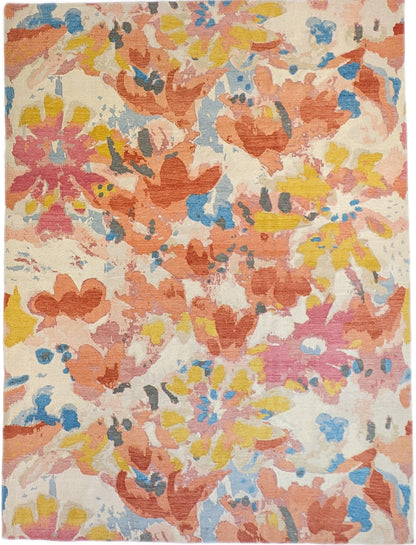 A hand-knotted rug with a floral pattern in a mix of pink, orange, yellow, blue, and gray hues.