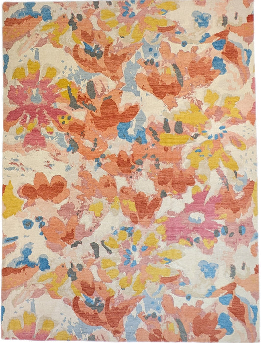 A hand-knotted rug with a floral pattern in a mix of pink, orange, yellow, blue, and gray hues.