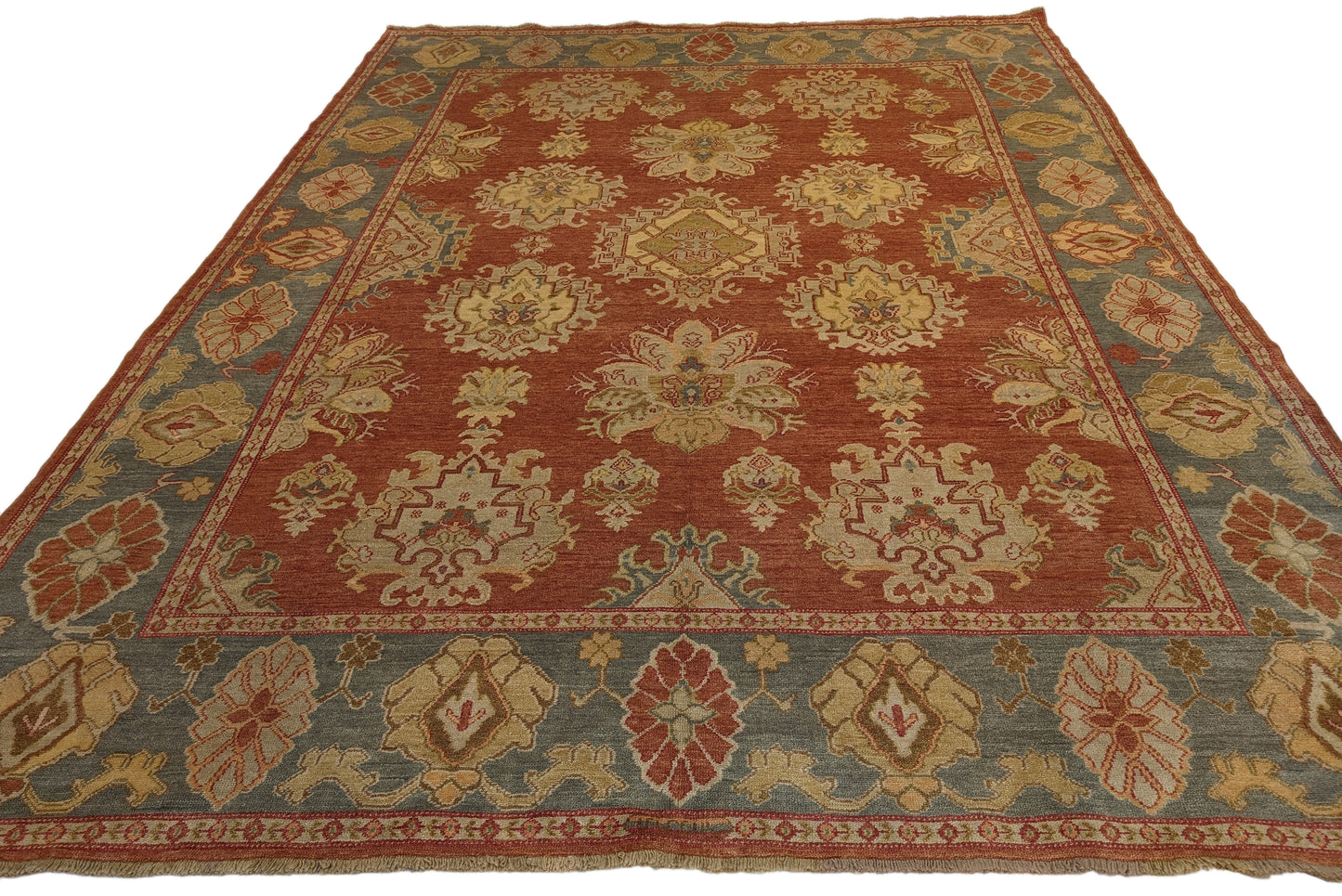A handmade rug with a classic geometric pattern featuring a mix of rosy pink, golden yellow, blue, beige, and ivory colors.