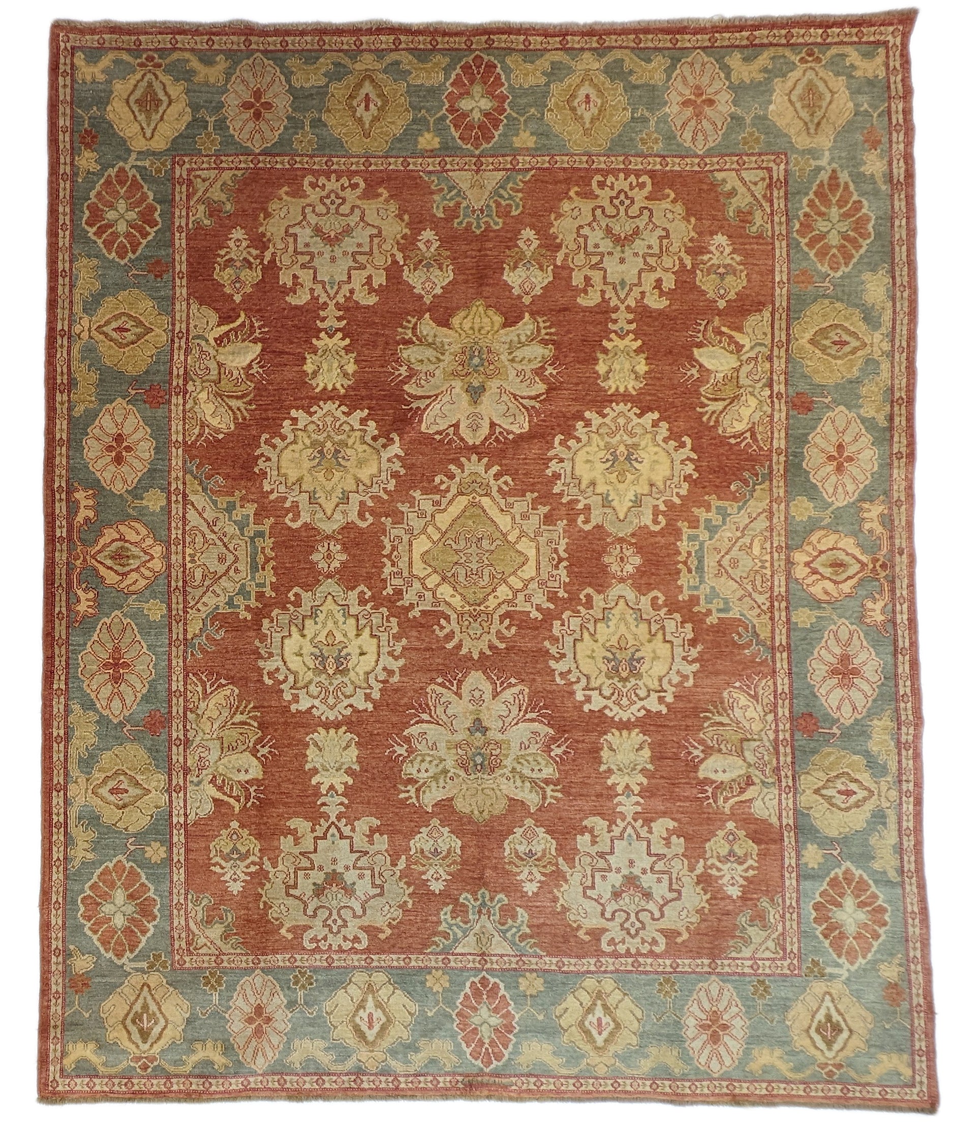 A handmade rug with a classic geometric pattern featuring a mix of rosy pink, golden yellow, blue, beige, and ivory colors.