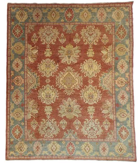 A handmade rug with a classic geometric pattern featuring a mix of rosy pink, golden yellow, blue, beige, and ivory colors.