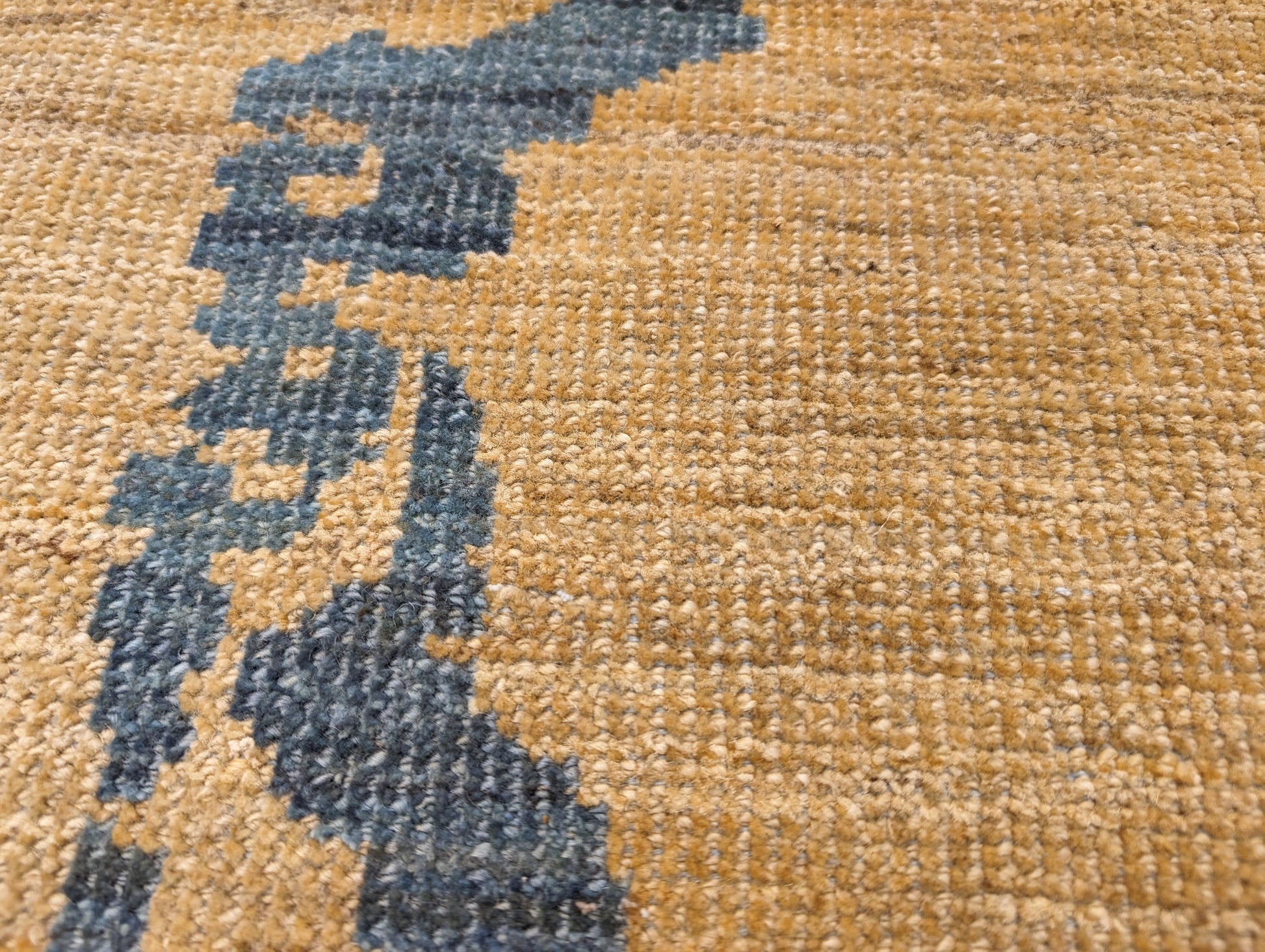 A hand-knotted wool rug with a geometric pattern in natural jute brown and muted aquamarine undertones. Low pile. 