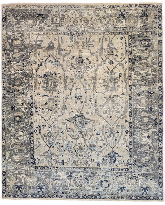 A hand-knotted silk rug with a coastal palette of grey, ivory, navy, light blue, and sandy taupe, featuring traditional and contemporary design elements.
