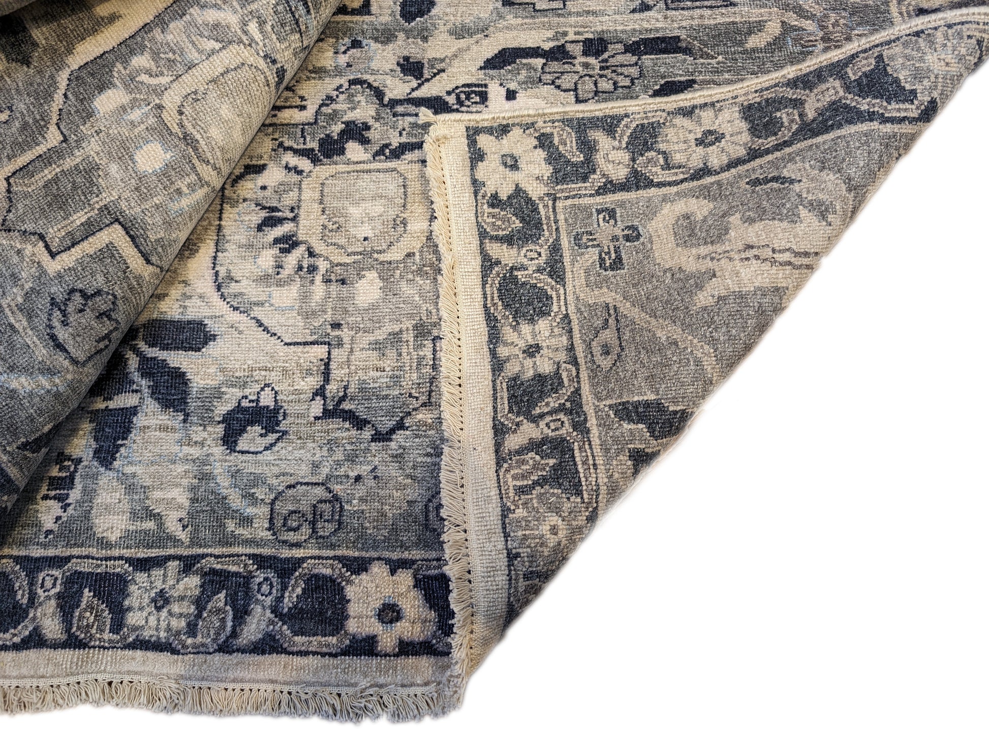 A hand-knotted silk rug with a coastal palette of grey, ivory, navy, light blue, and sandy taupe, featuring traditional and contemporary design elements.