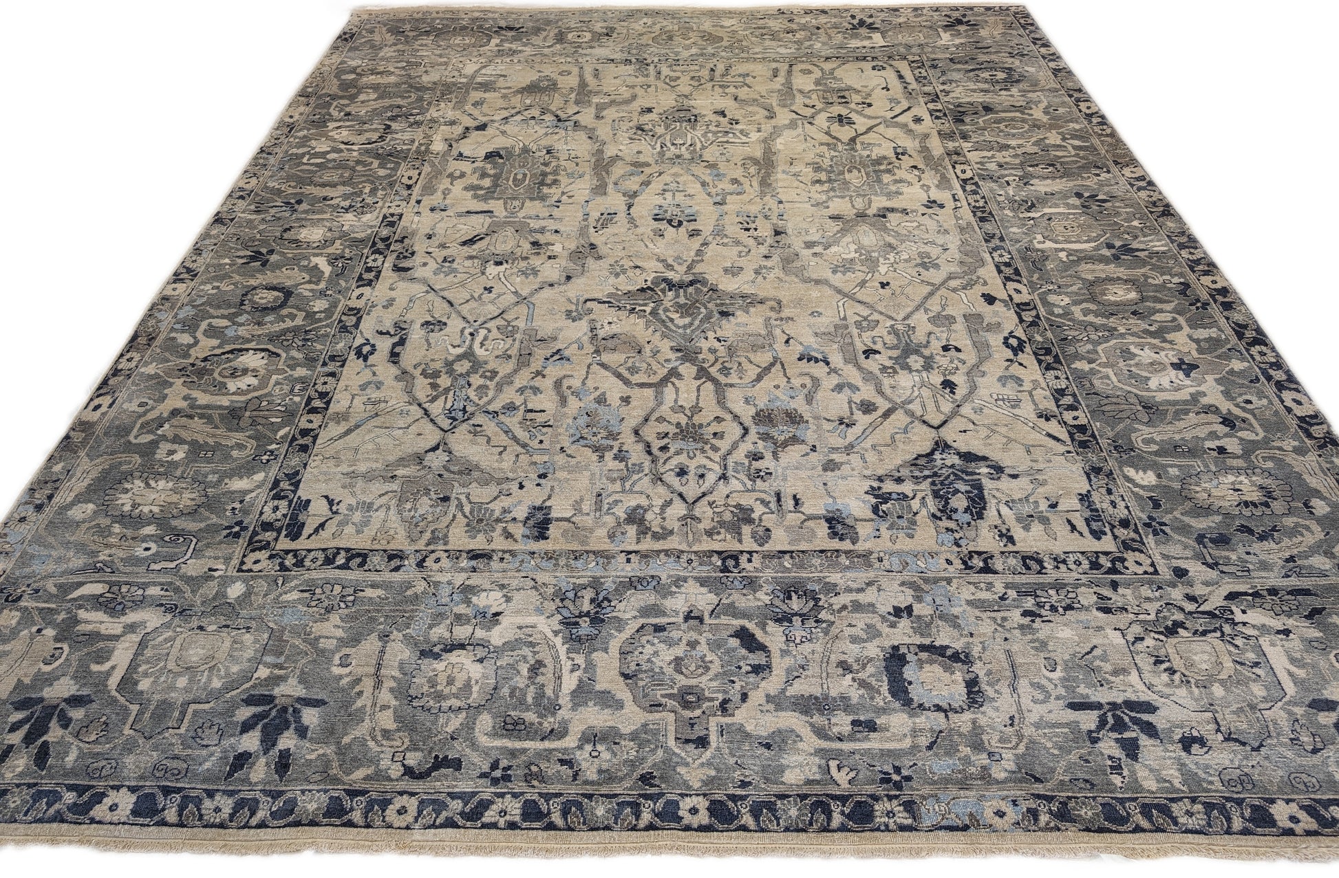 A hand-knotted silk rug with a coastal palette of grey, ivory, navy, light blue, and sandy taupe, featuring traditional and contemporary design elements.