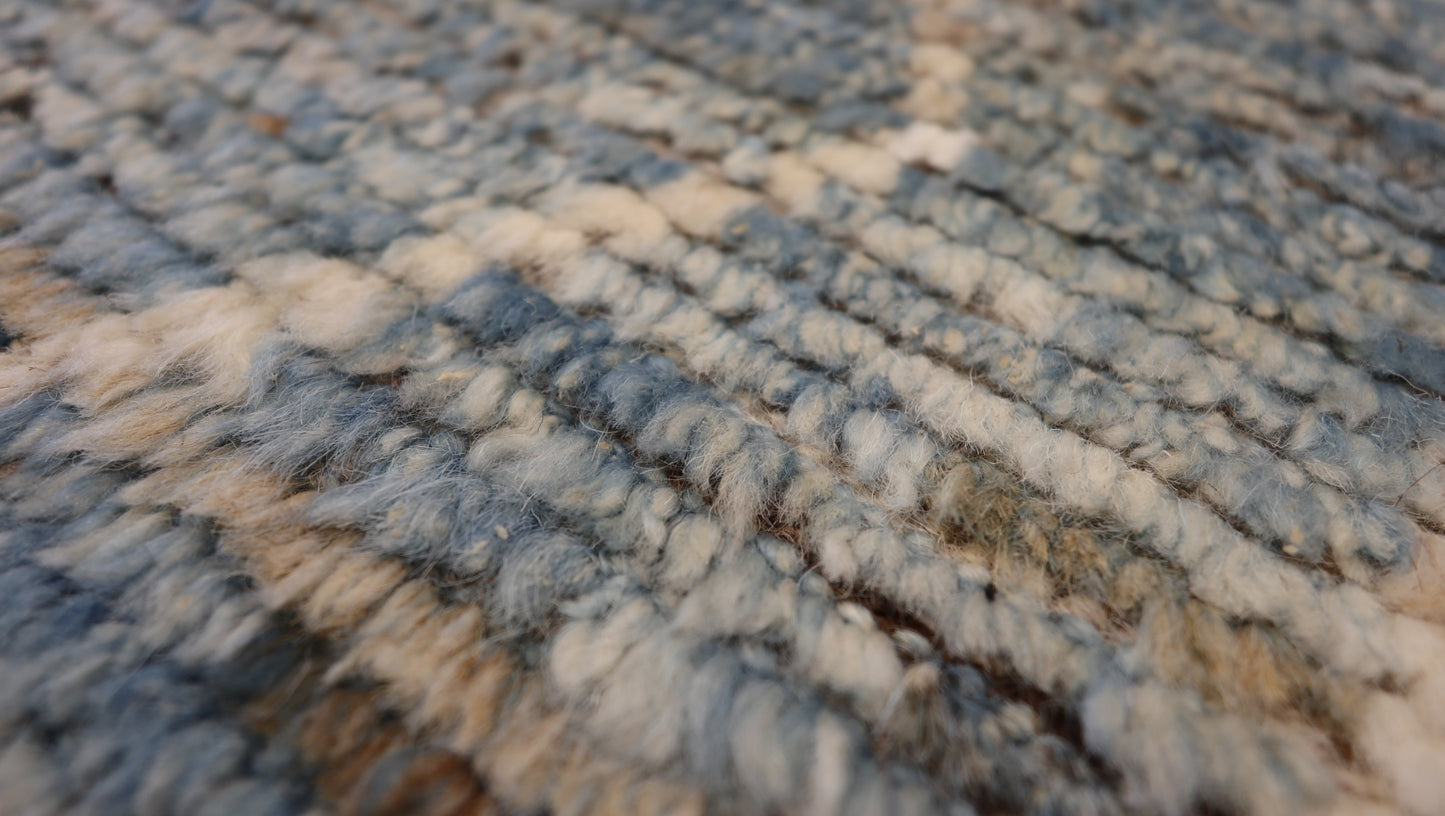 Hand-knotted geometric wool rug with a high pile and large knots in blue, ivory, beige, grey, and brown.