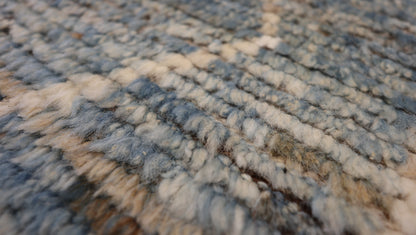 Hand-knotted geometric wool rug with a high pile and large knots in blue, ivory, beige, grey, and brown.