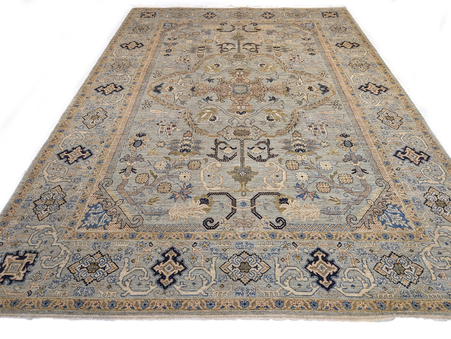 A hand-knotted wool rug with a coastal palette of beige, navy, rosy pink, blue, gold, and ivory colors, featuring intricate traditional and contemporary patterns.