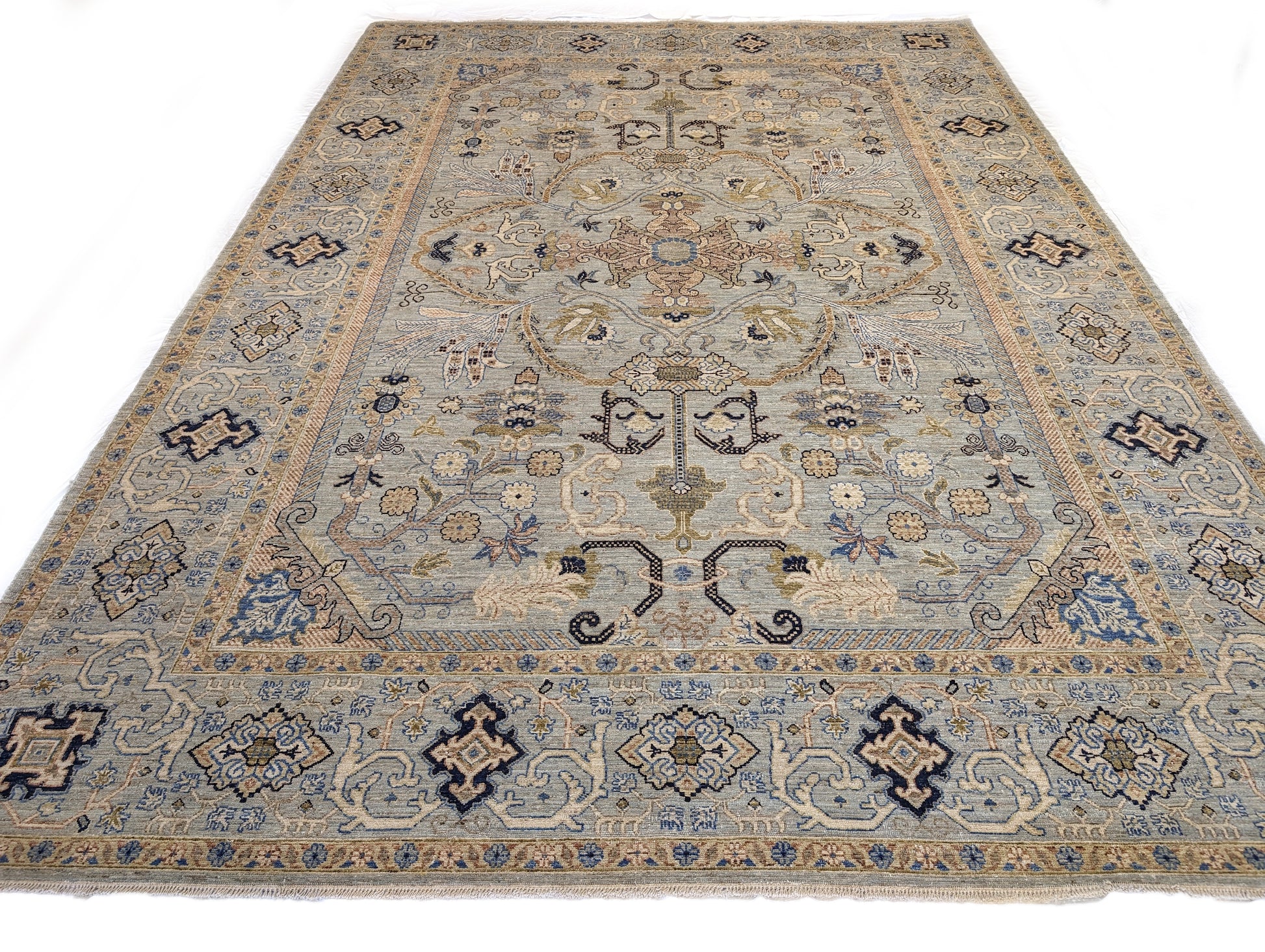 A hand-knotted wool rug with a coastal palette of beige, navy, rosy pink, blue, gold, and ivory colors, featuring intricate traditional and contemporary patterns.